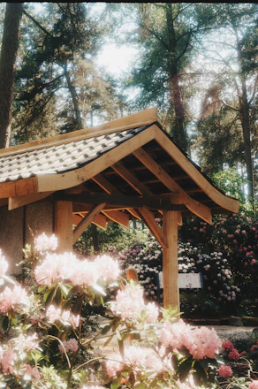 a wooden gazebo surrounded by flowers and trees
