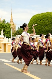 a group of women in thai garb dancing in a street