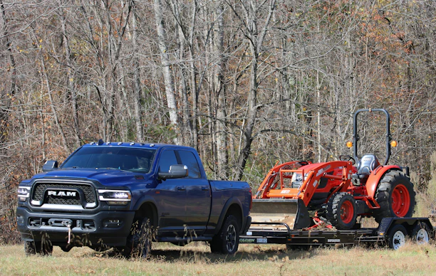 a blue pickup truck towing a red tractor