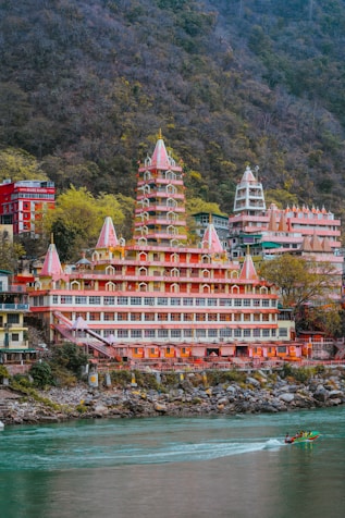 a boat traveling down a river ganga next to a Temple in Rishikesh