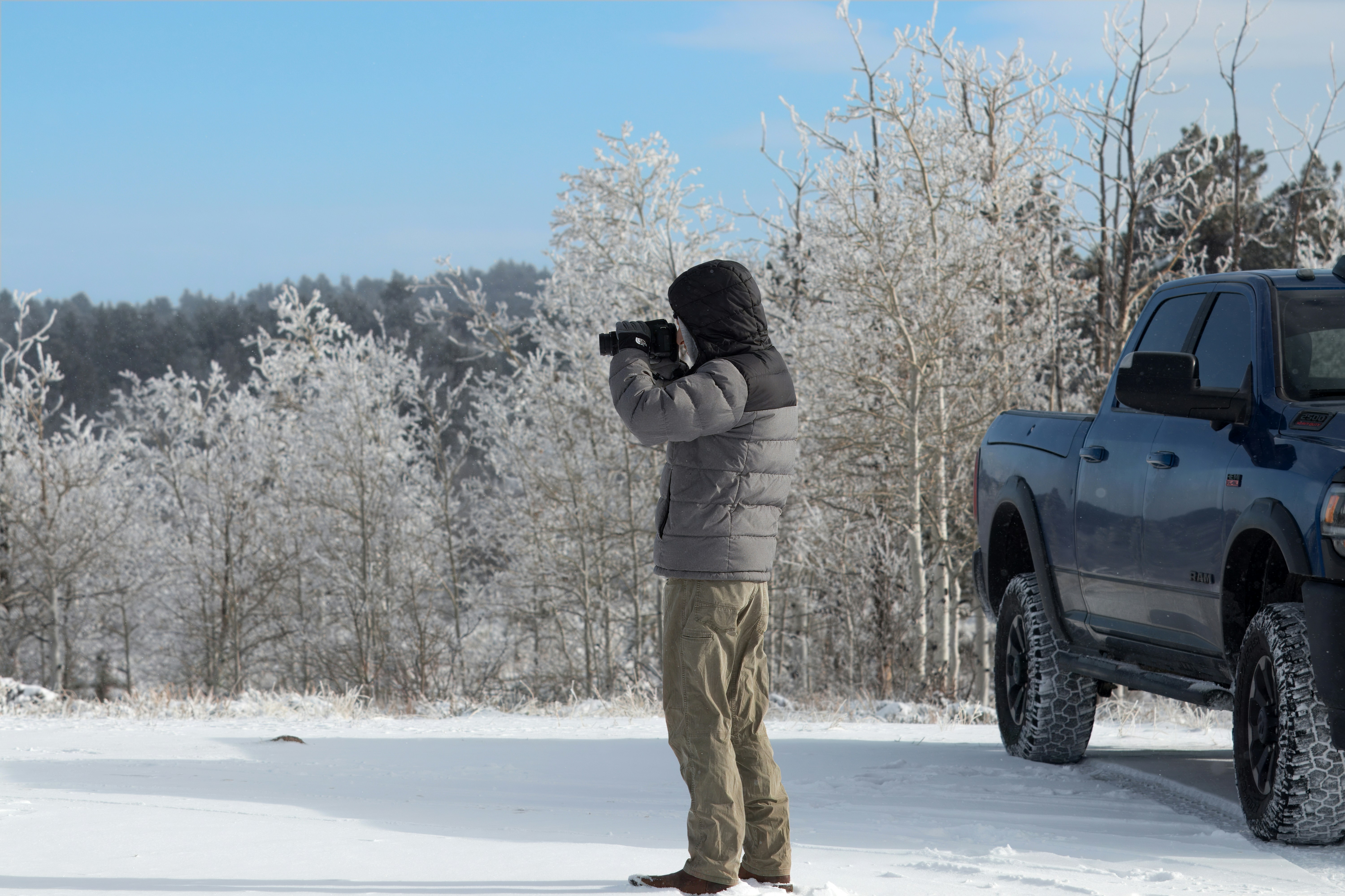 雪の中でトラックの写真を撮る男性