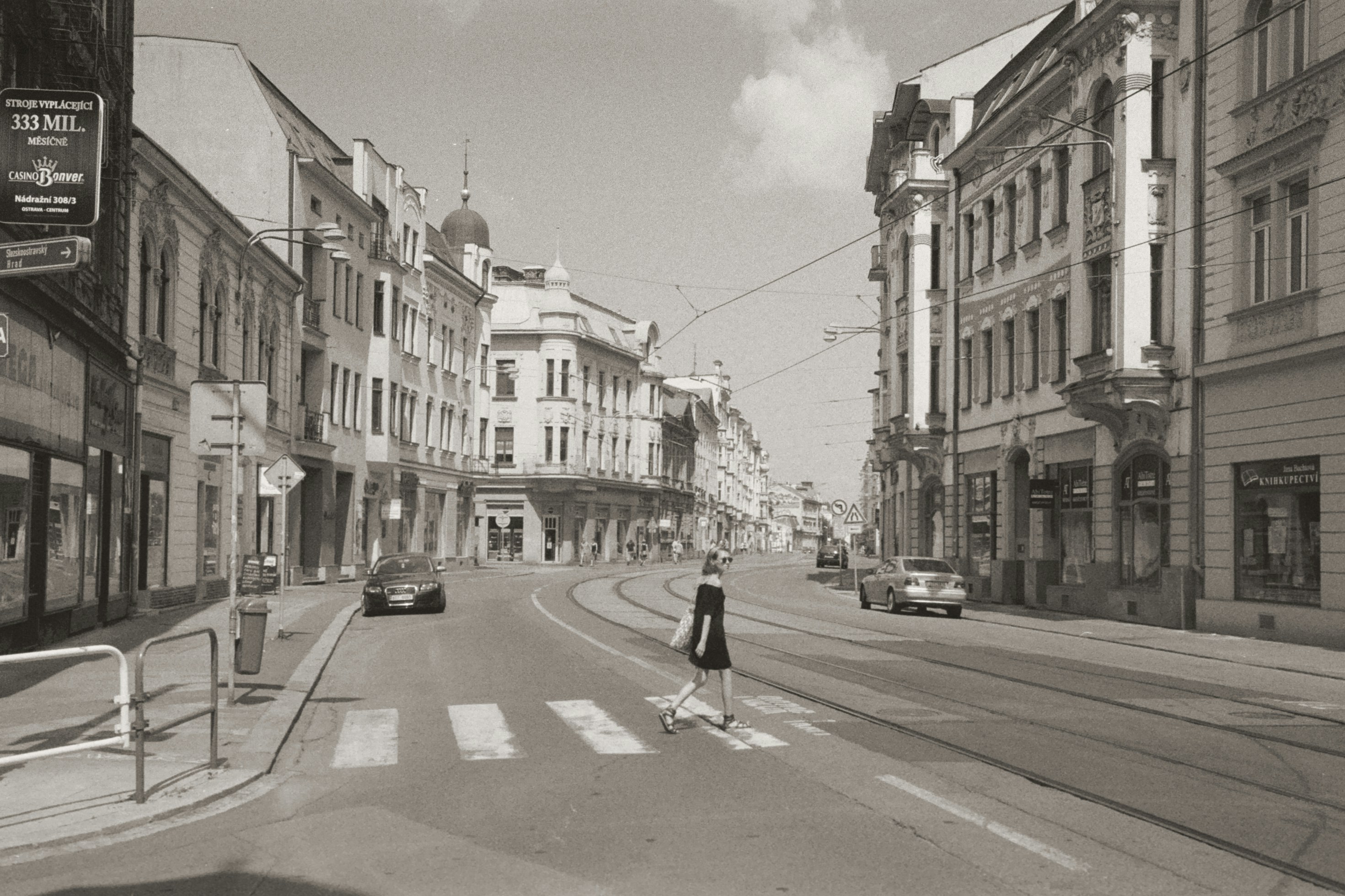 a black and white photo of a woman crossing the street