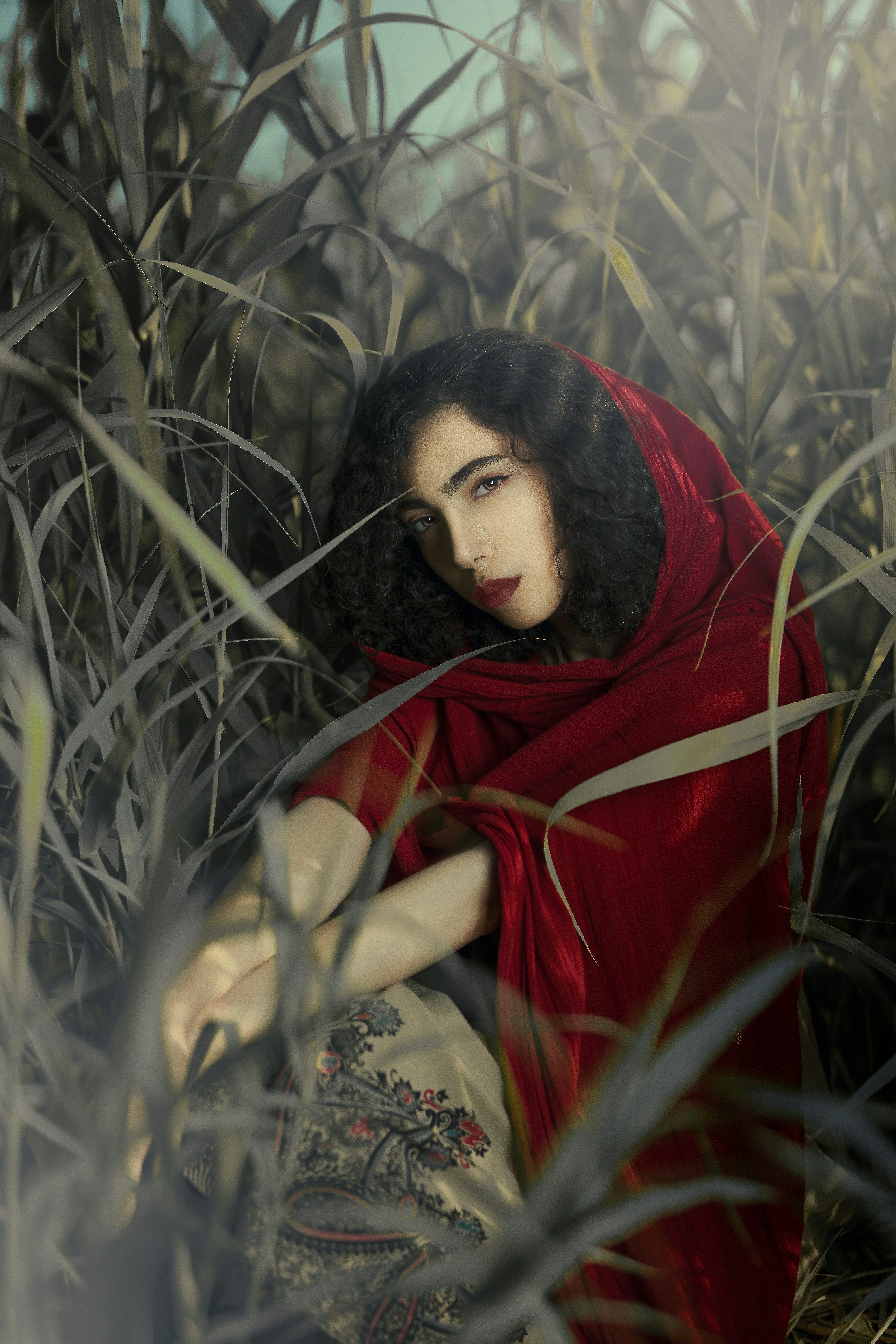 a woman in a red dress sitting in tall grass