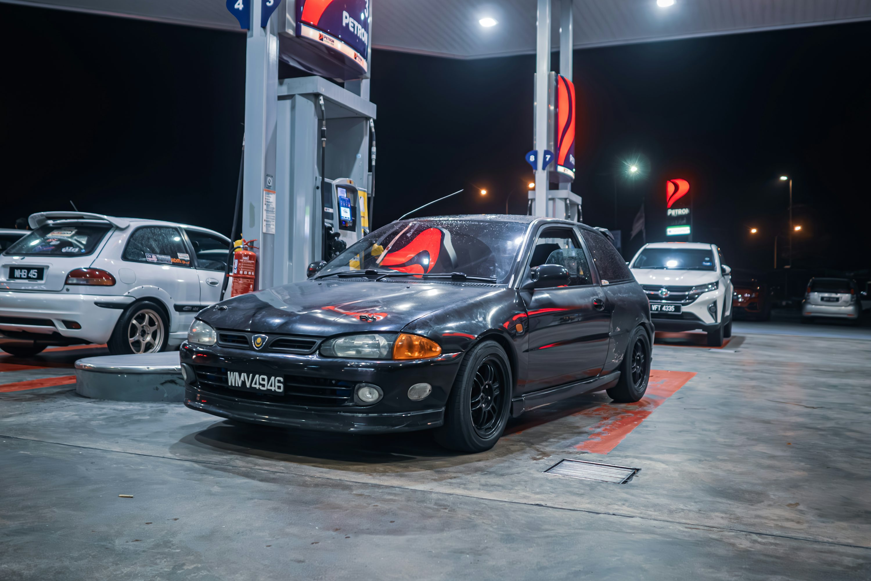 a couple of cars are parked at a gas station
