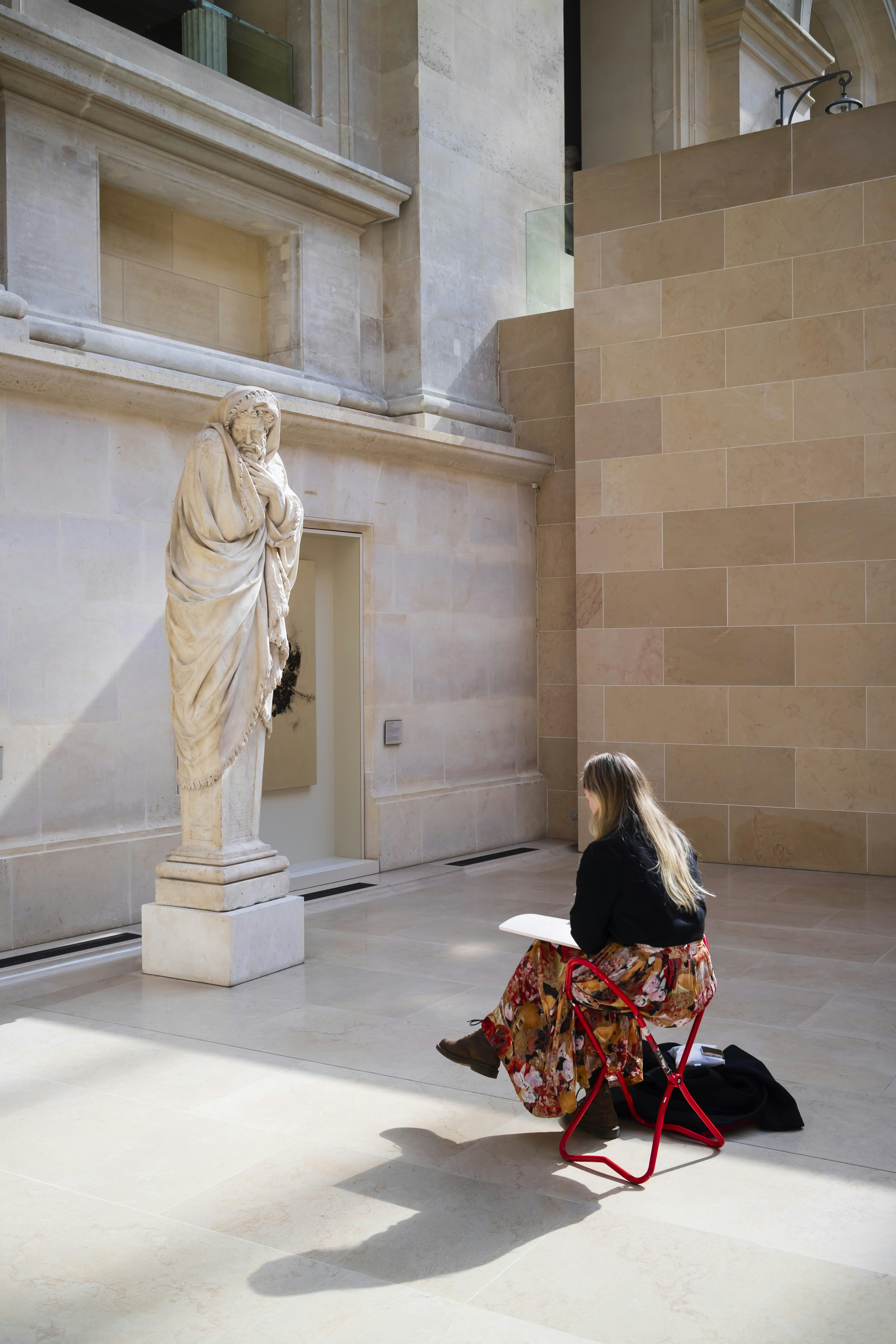 a woman sitting on a chair in front of a statue