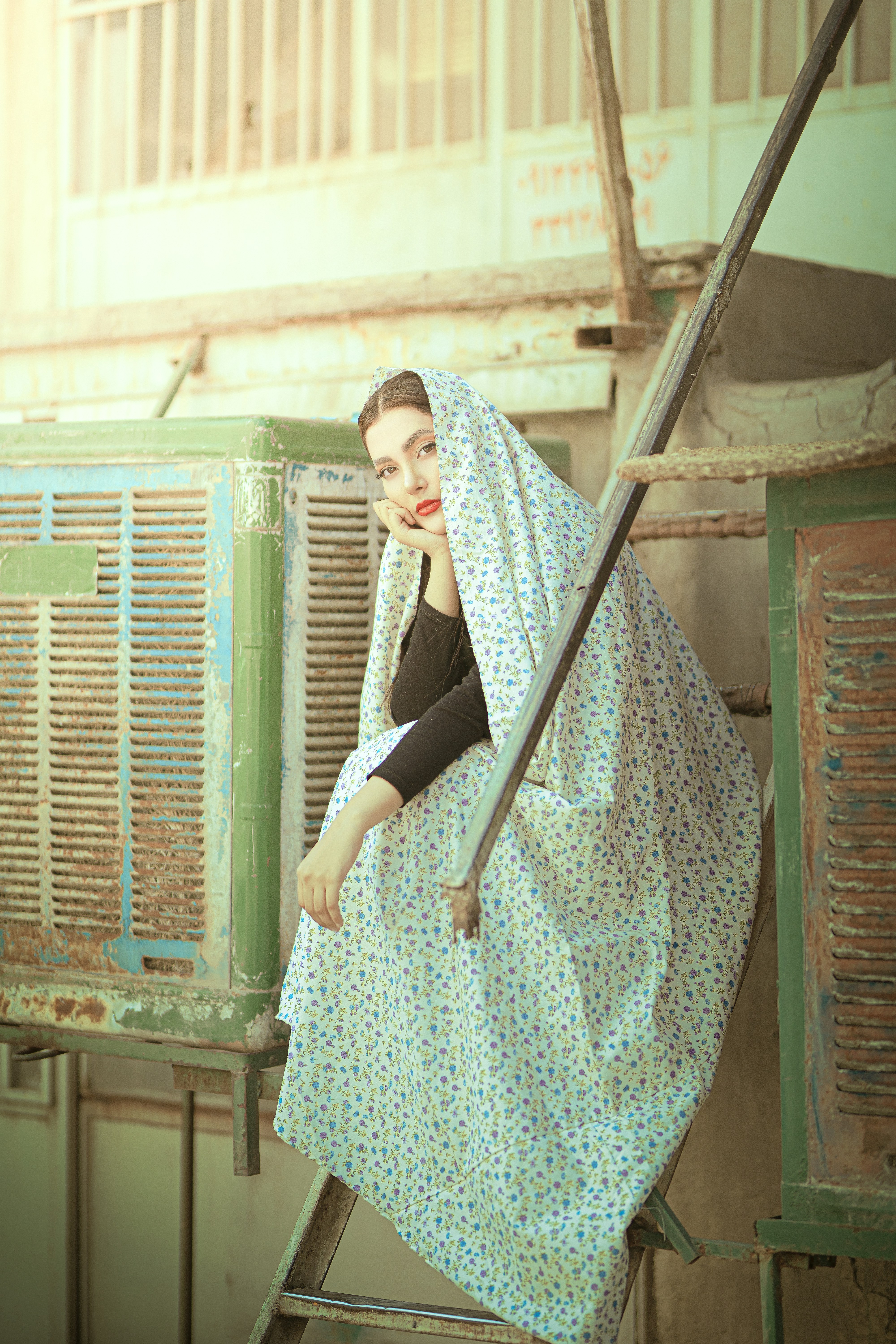 a woman standing on a ladder with a blanket over her head