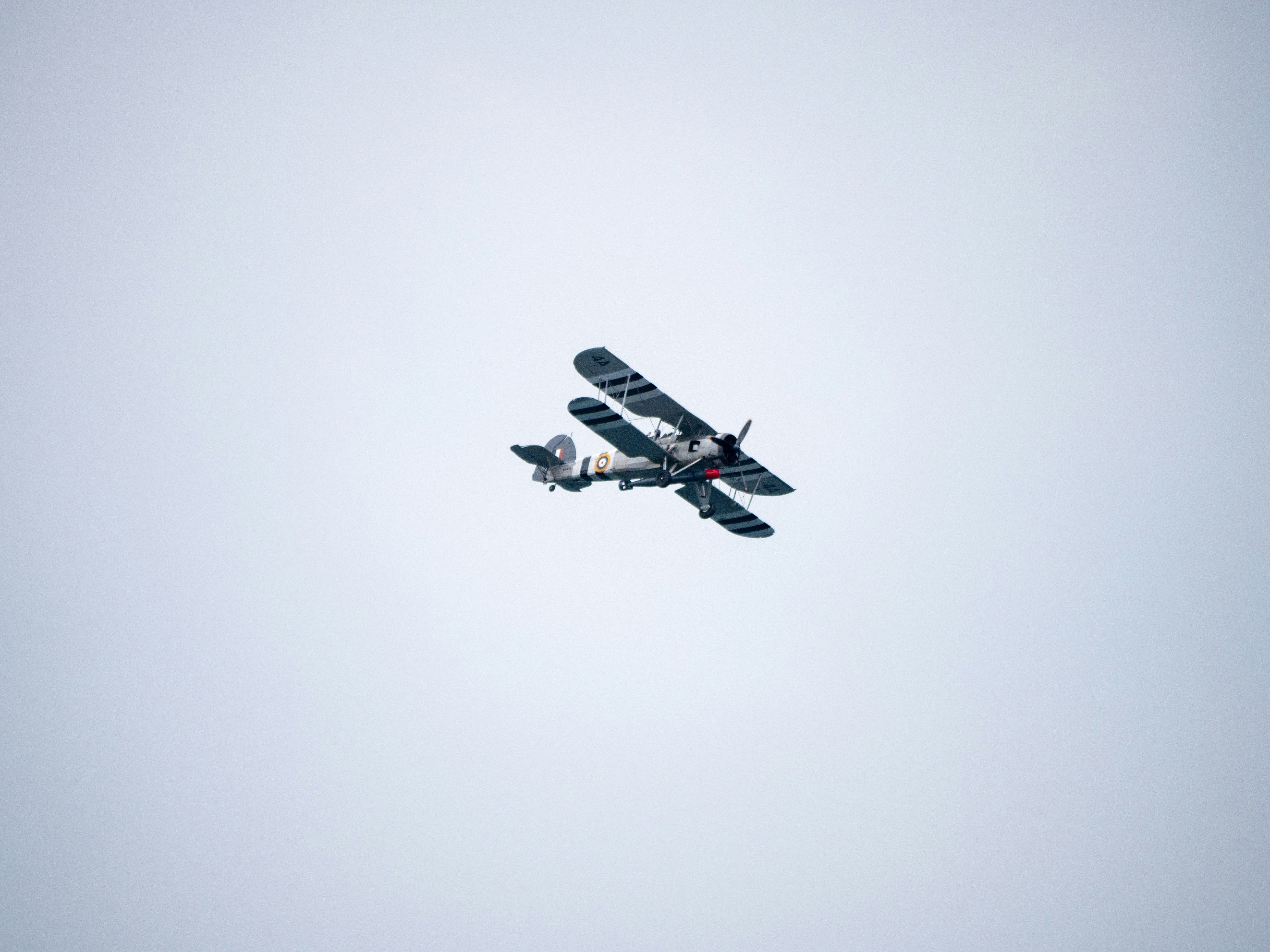 a small airplane flying through a gray sky
