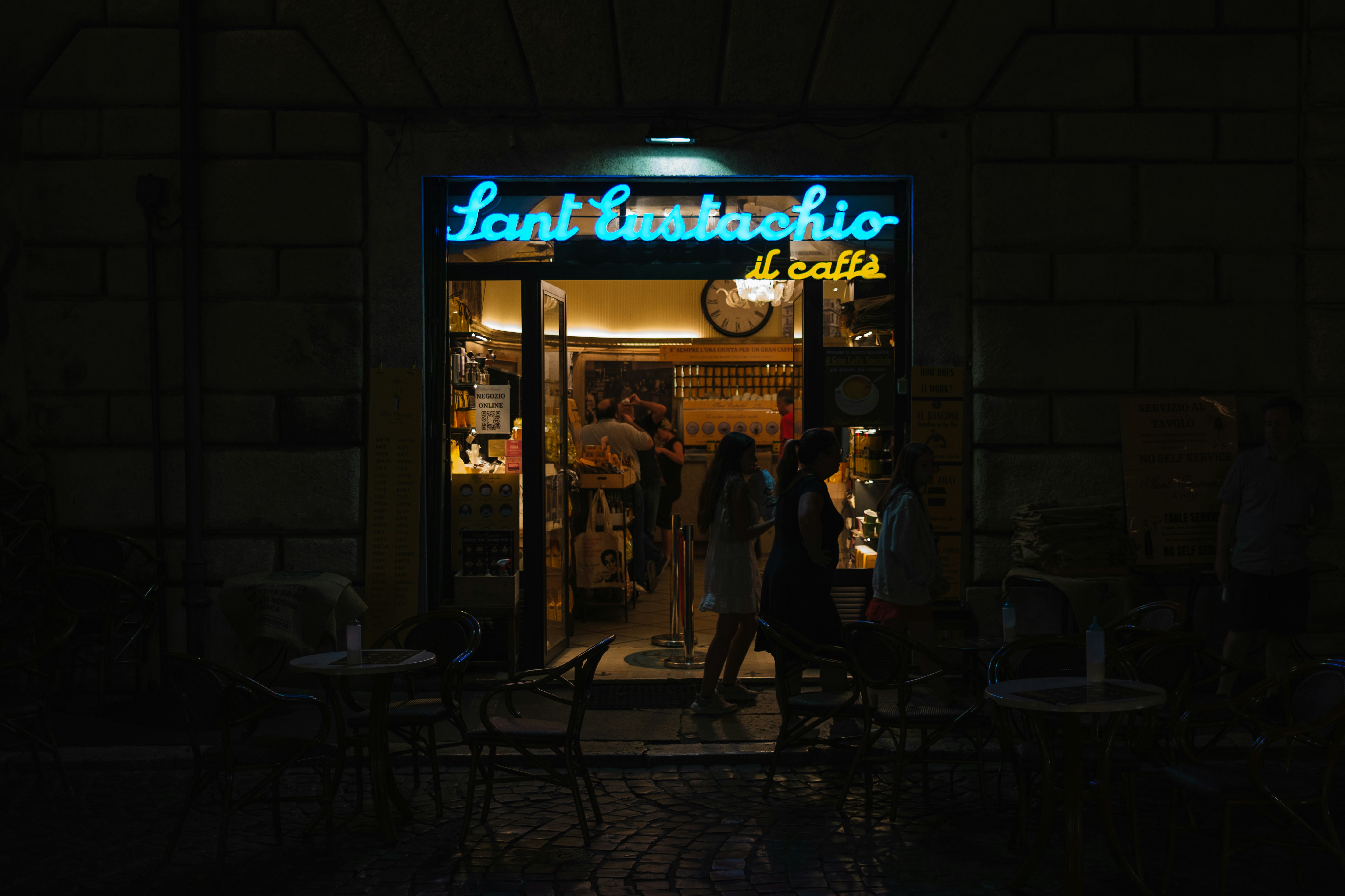 a group of people standing outside of a restaurant at night