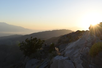 the sun is setting on a rocky mountain
