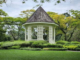 a white gazebo surrounded by lush green trees