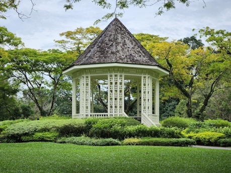 a white gazebo surrounded by lush green trees