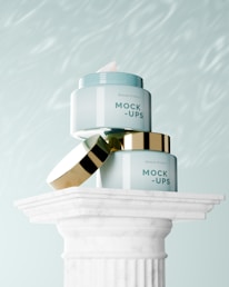 a close up of two jars of makeup on top of a pillar