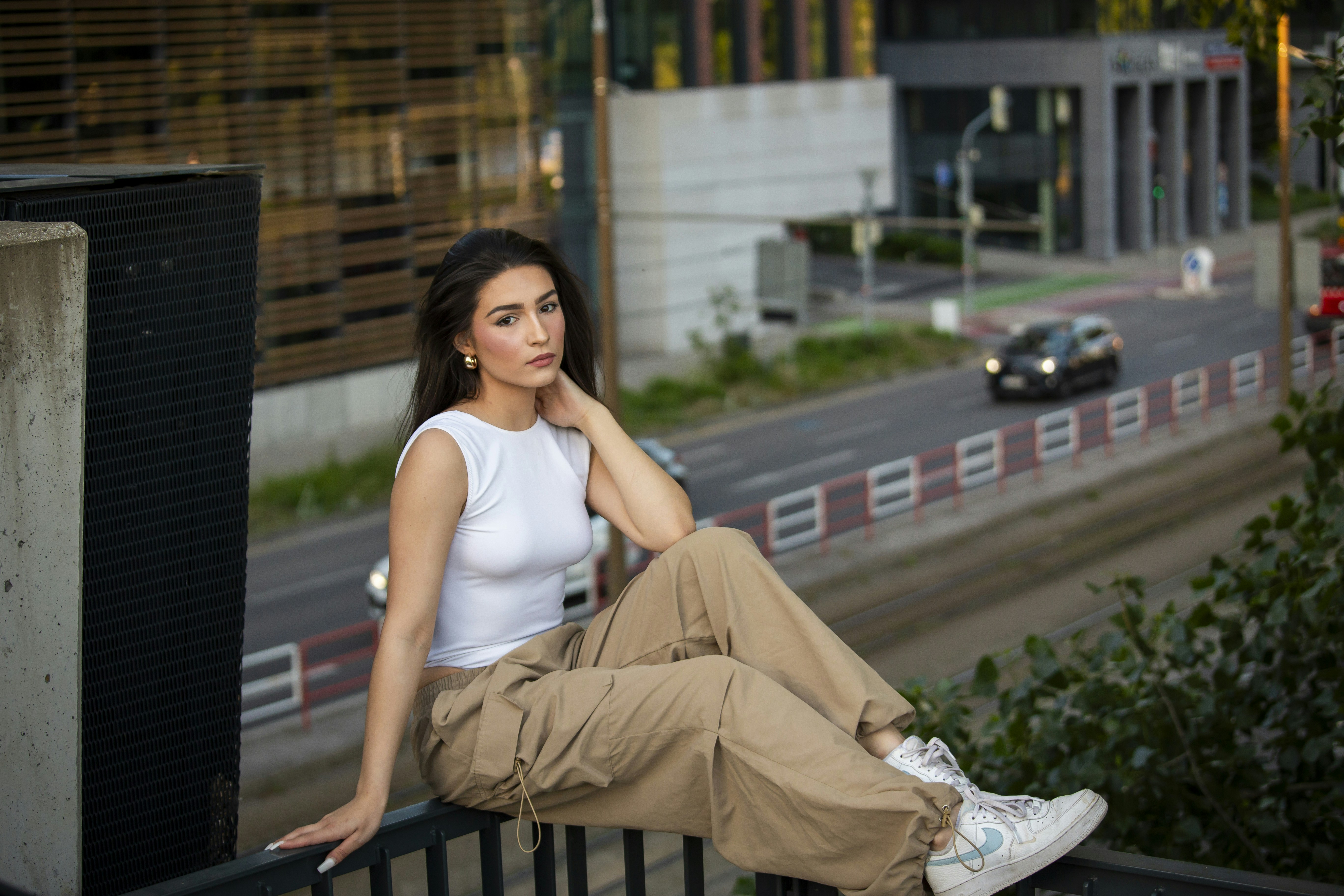 una donna seduta su una ringhiera accanto a una strada
