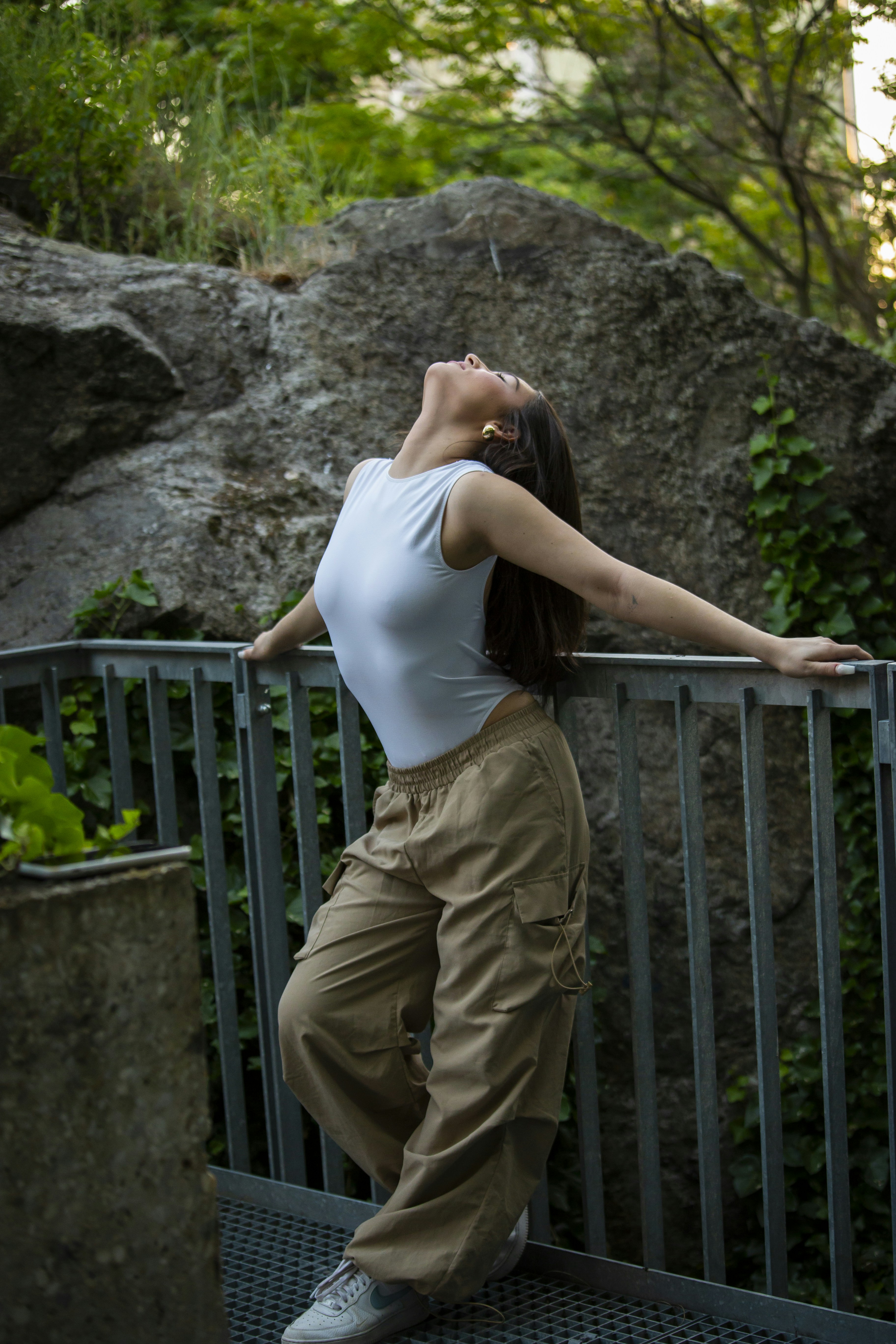 una donna appoggiata a una ringhiera in un parco