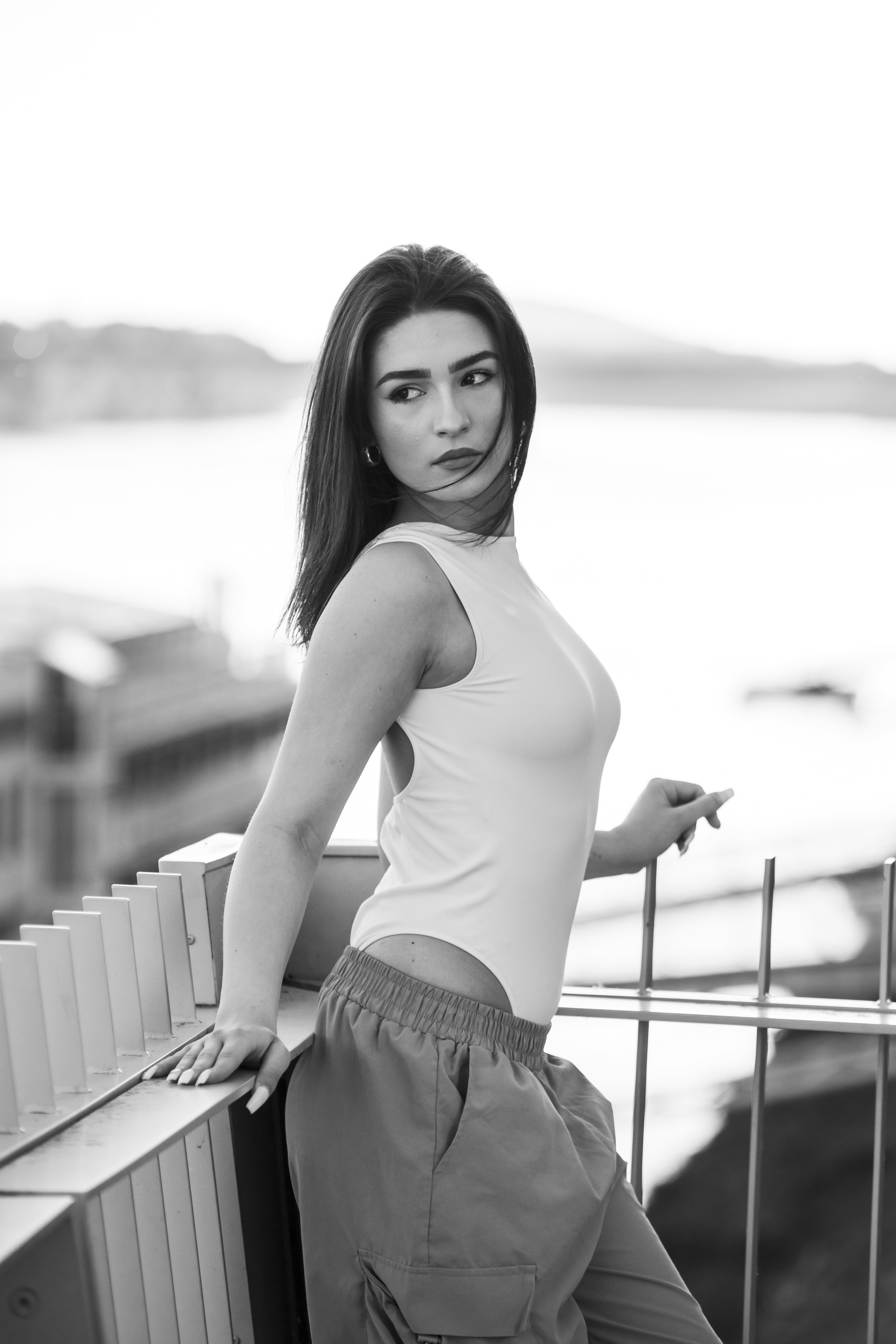 una donna appoggiata a una staccionata con le mani sui fianchi