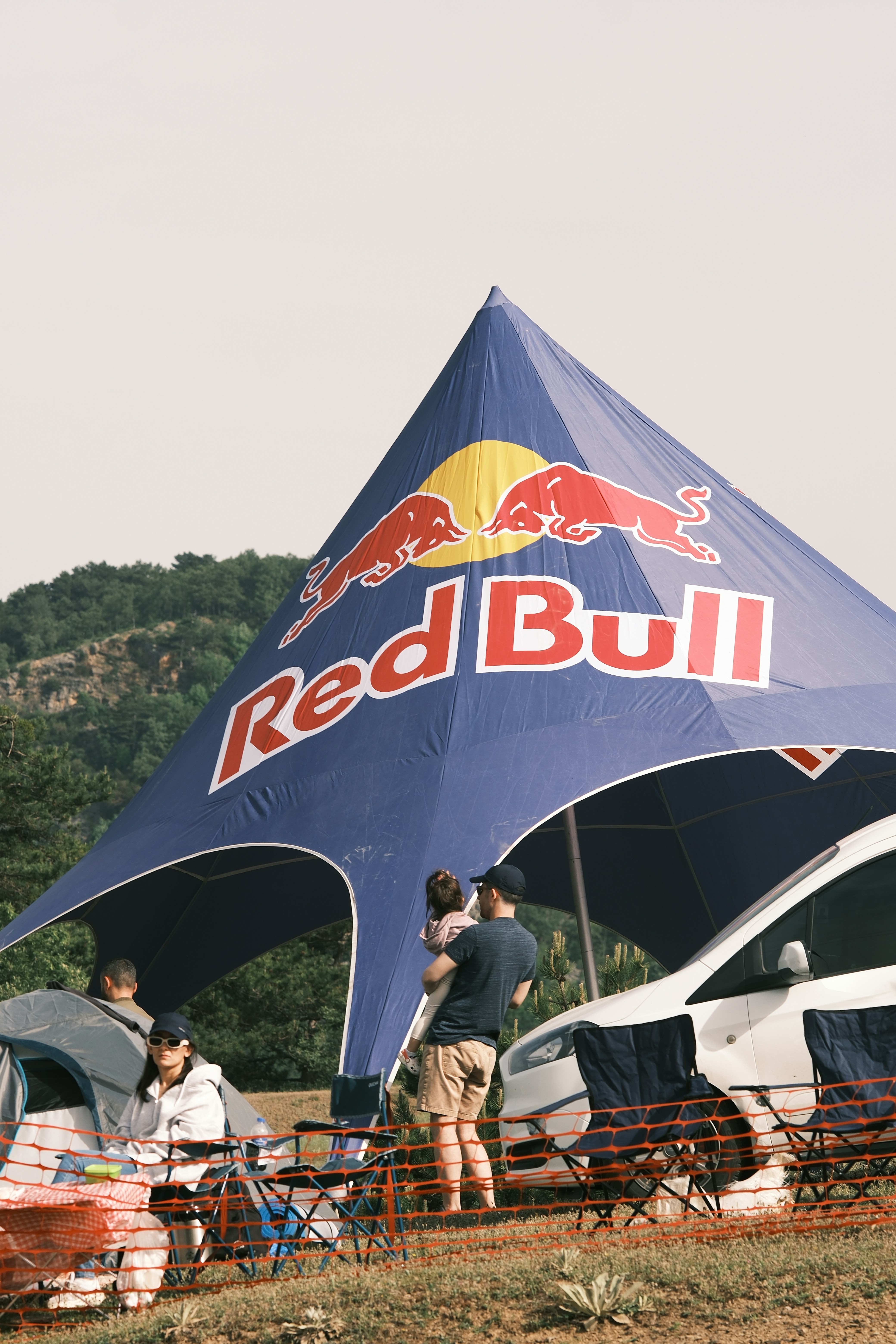 A group of people standing under a red bull tent