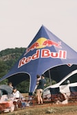A group of people standing under a red bull tent