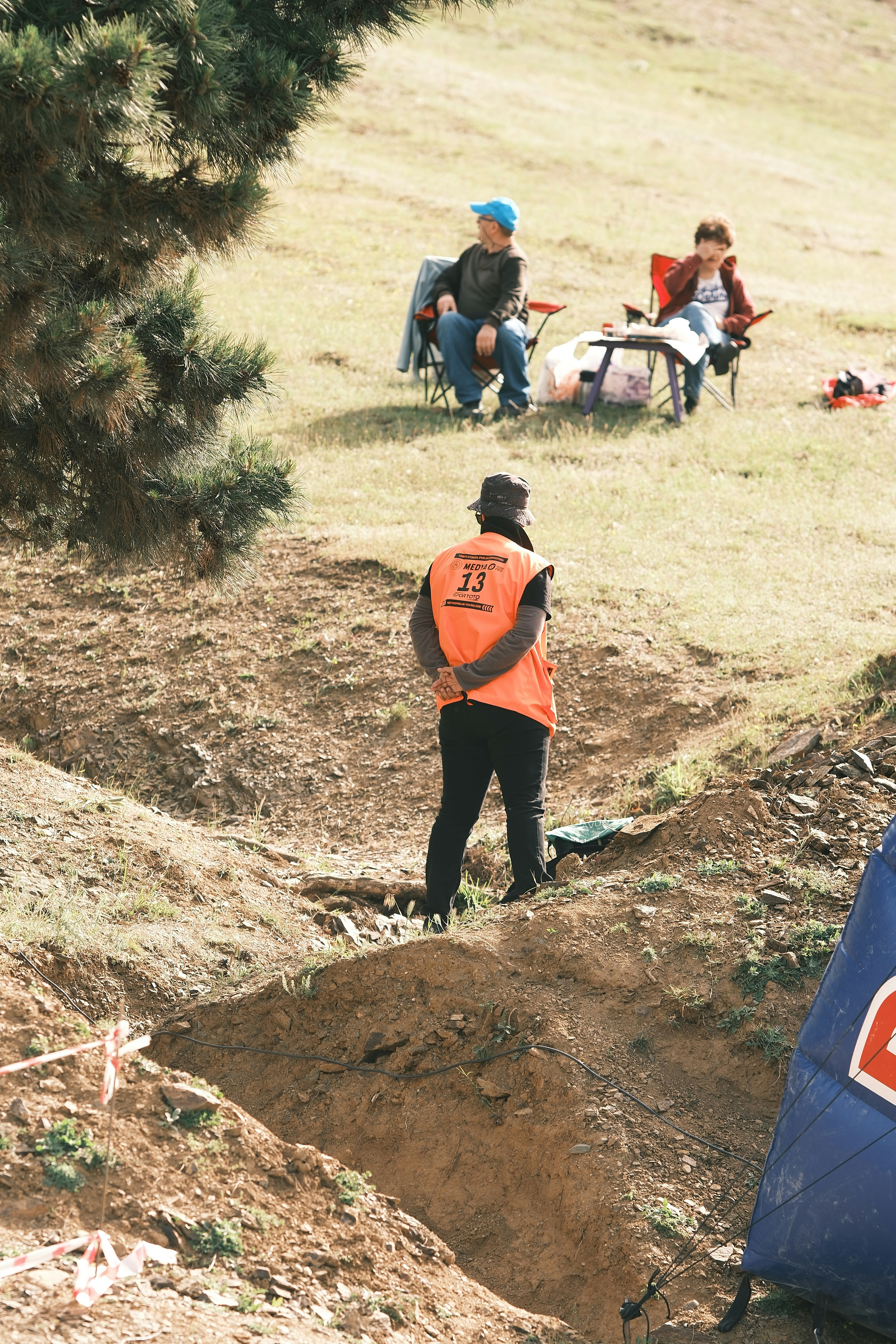 A man in an orange vest standing next to a blue sign