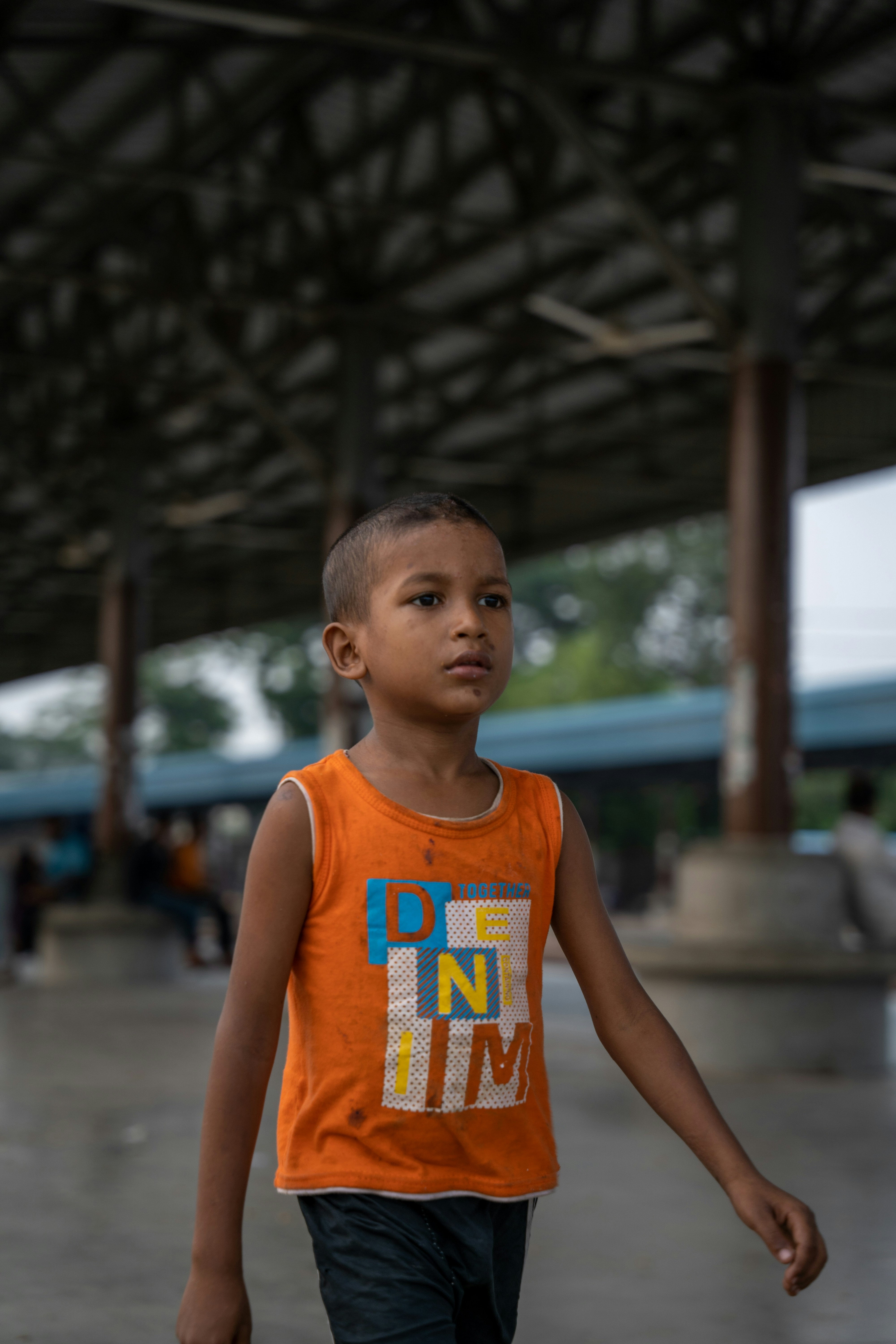a young boy in an orange shirt is walking