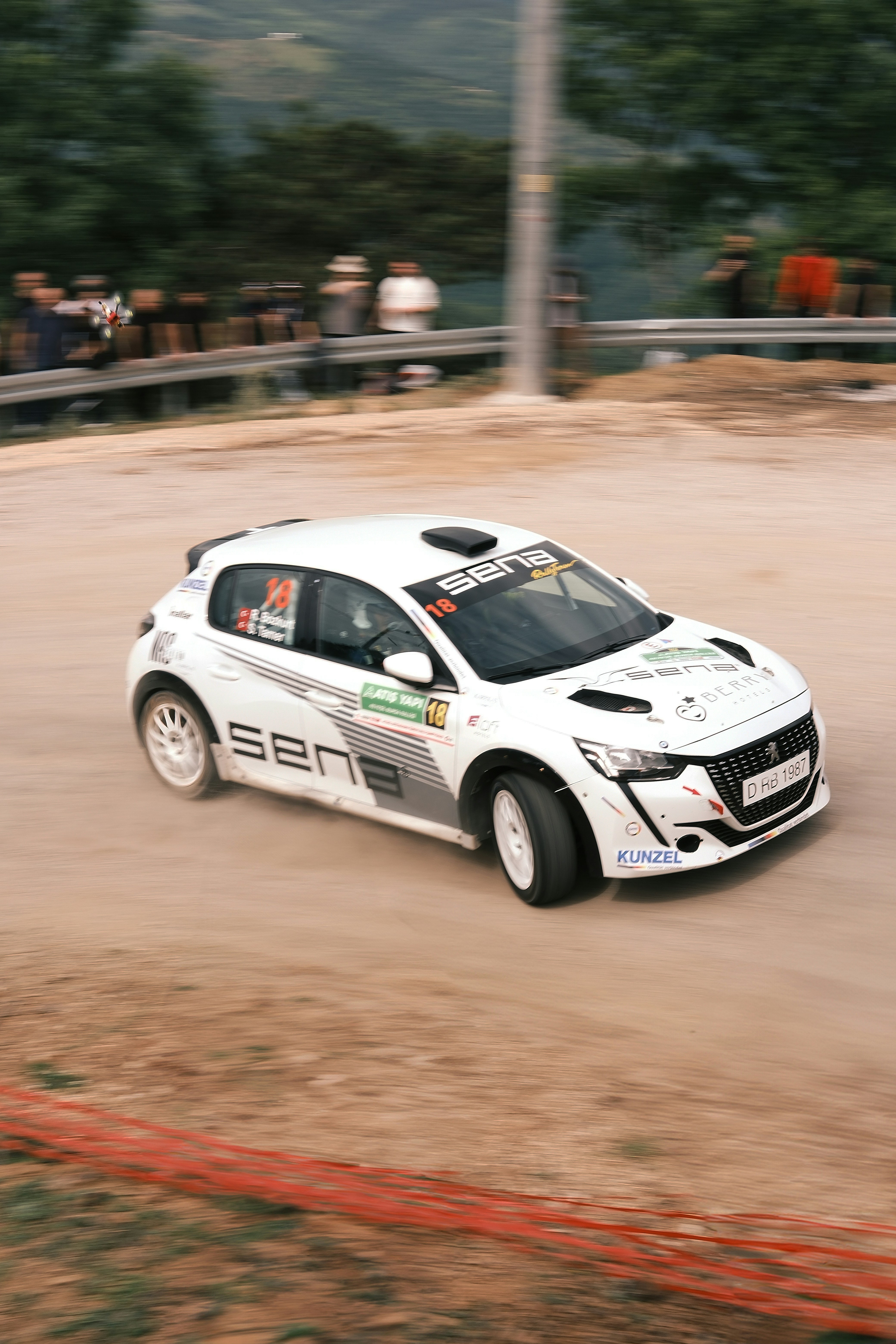 A white car driving down a dirt road