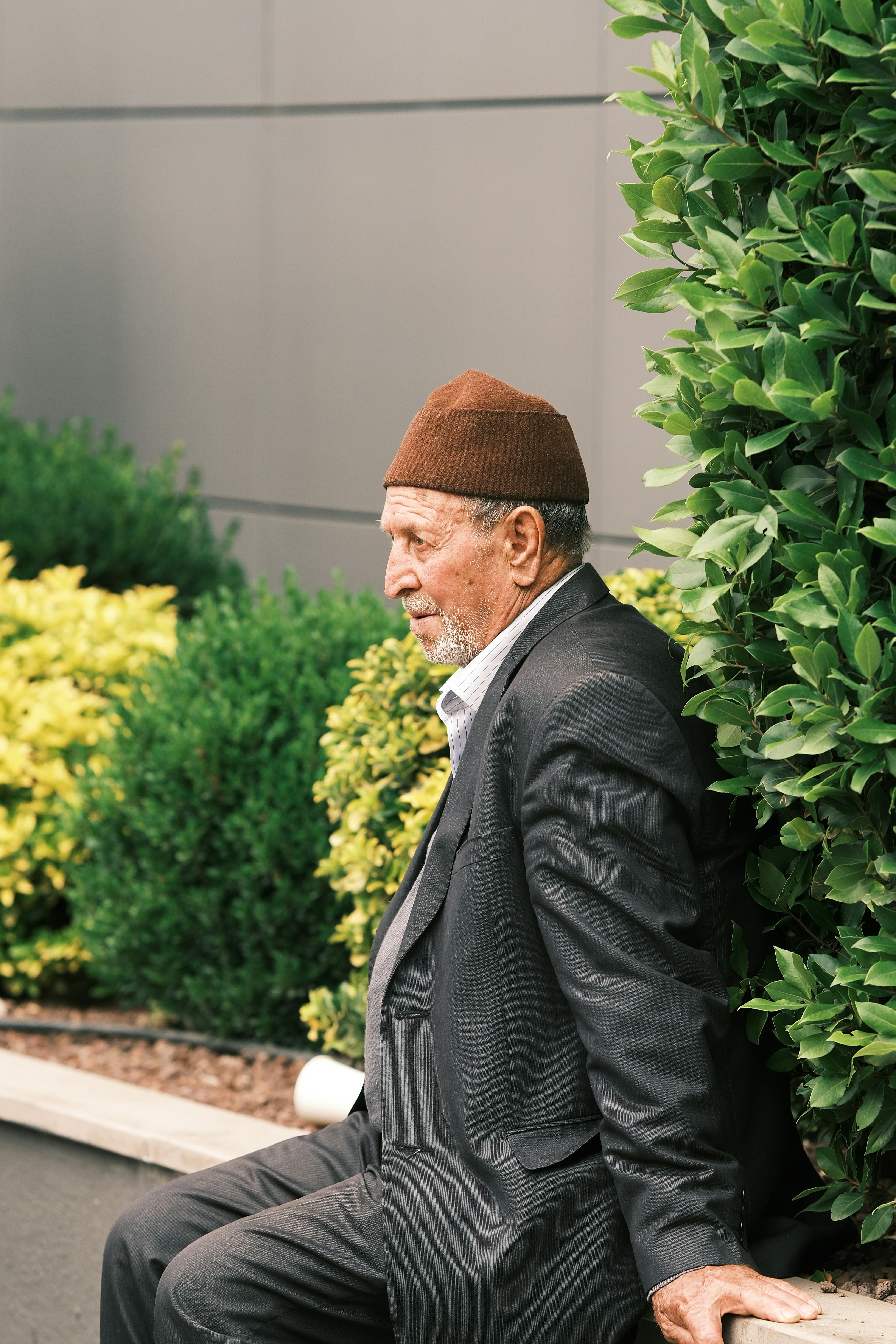 A man in a suit and hat sitting on a bench