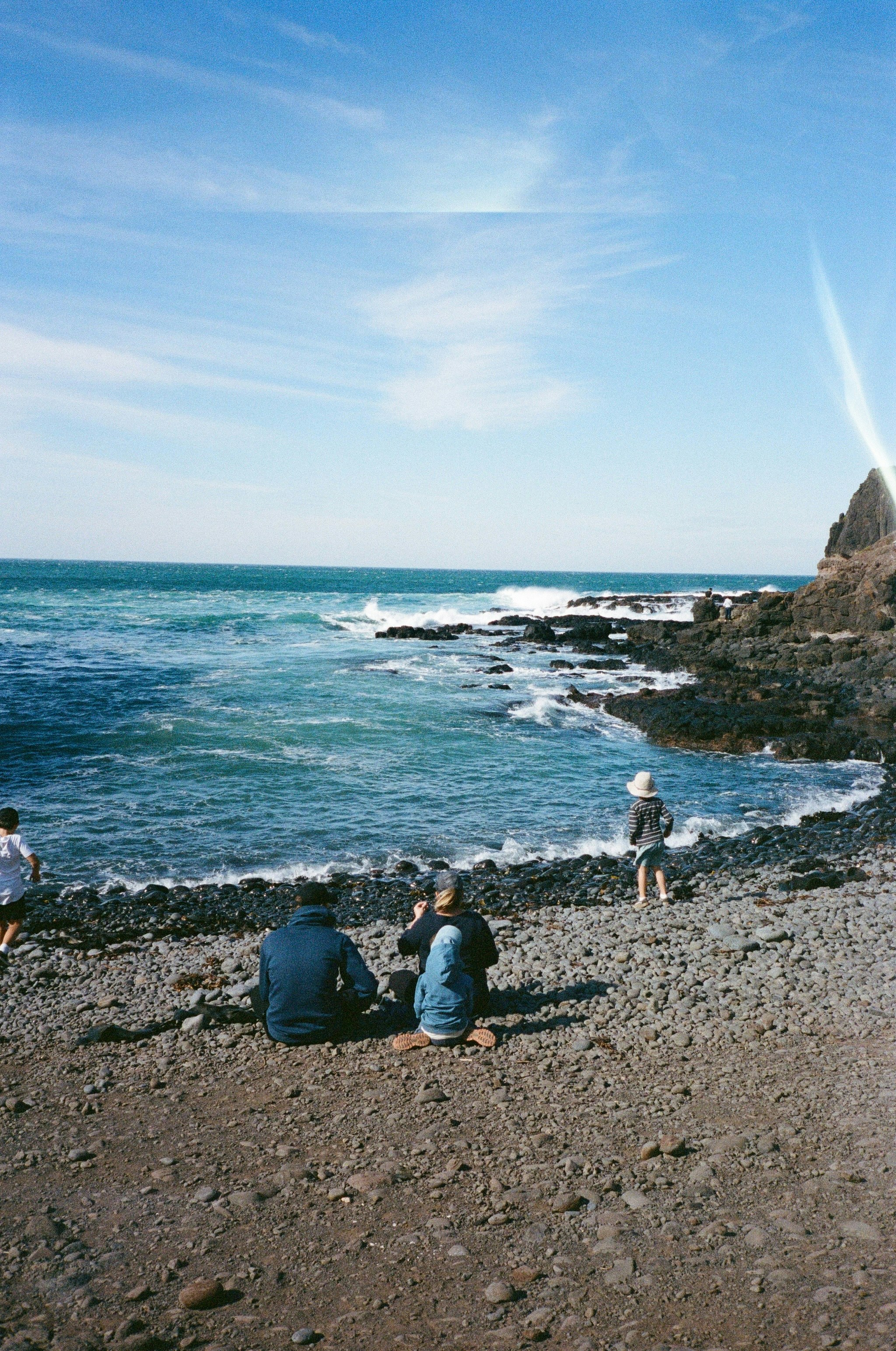 a group of people sitting on a beach next to the ocean