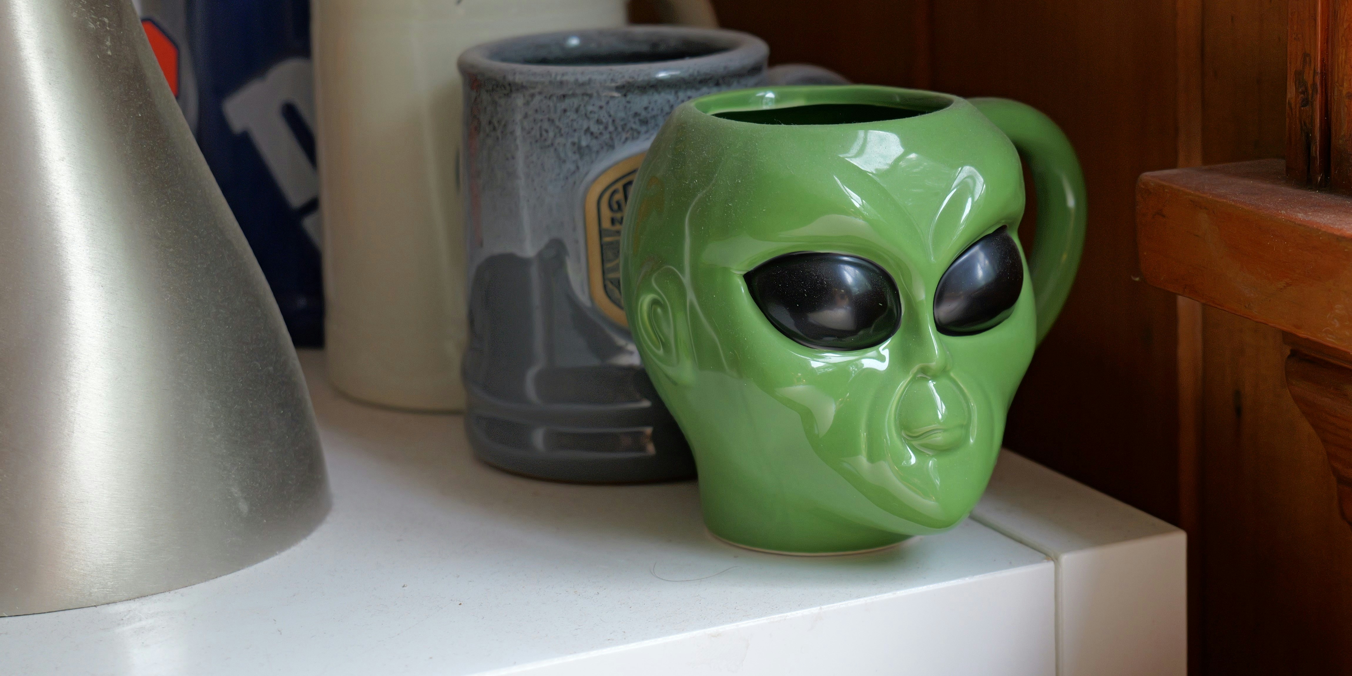 A green alien mug sitting on top of a counter