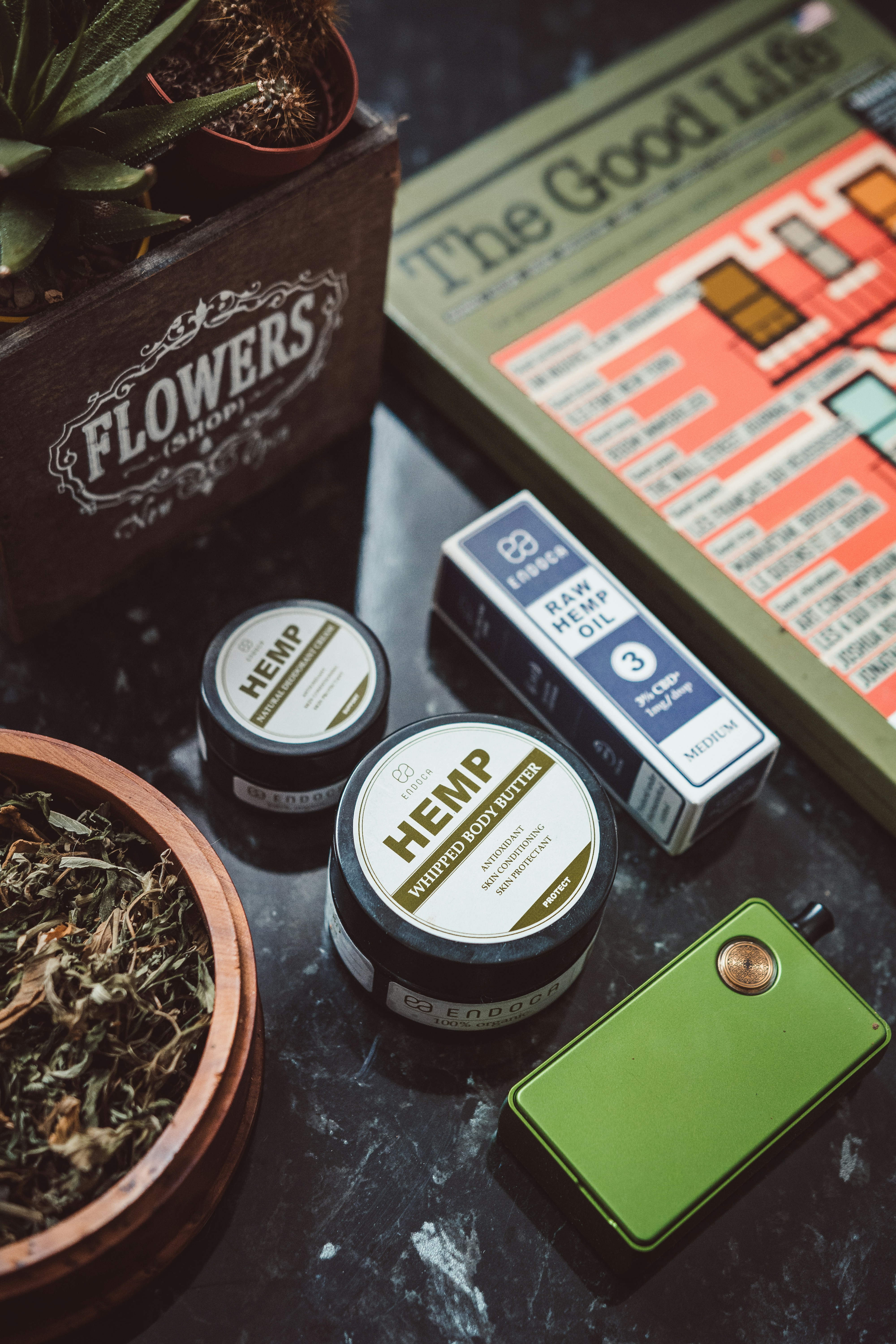 Hemp skincare products and vape pen on a dark table.