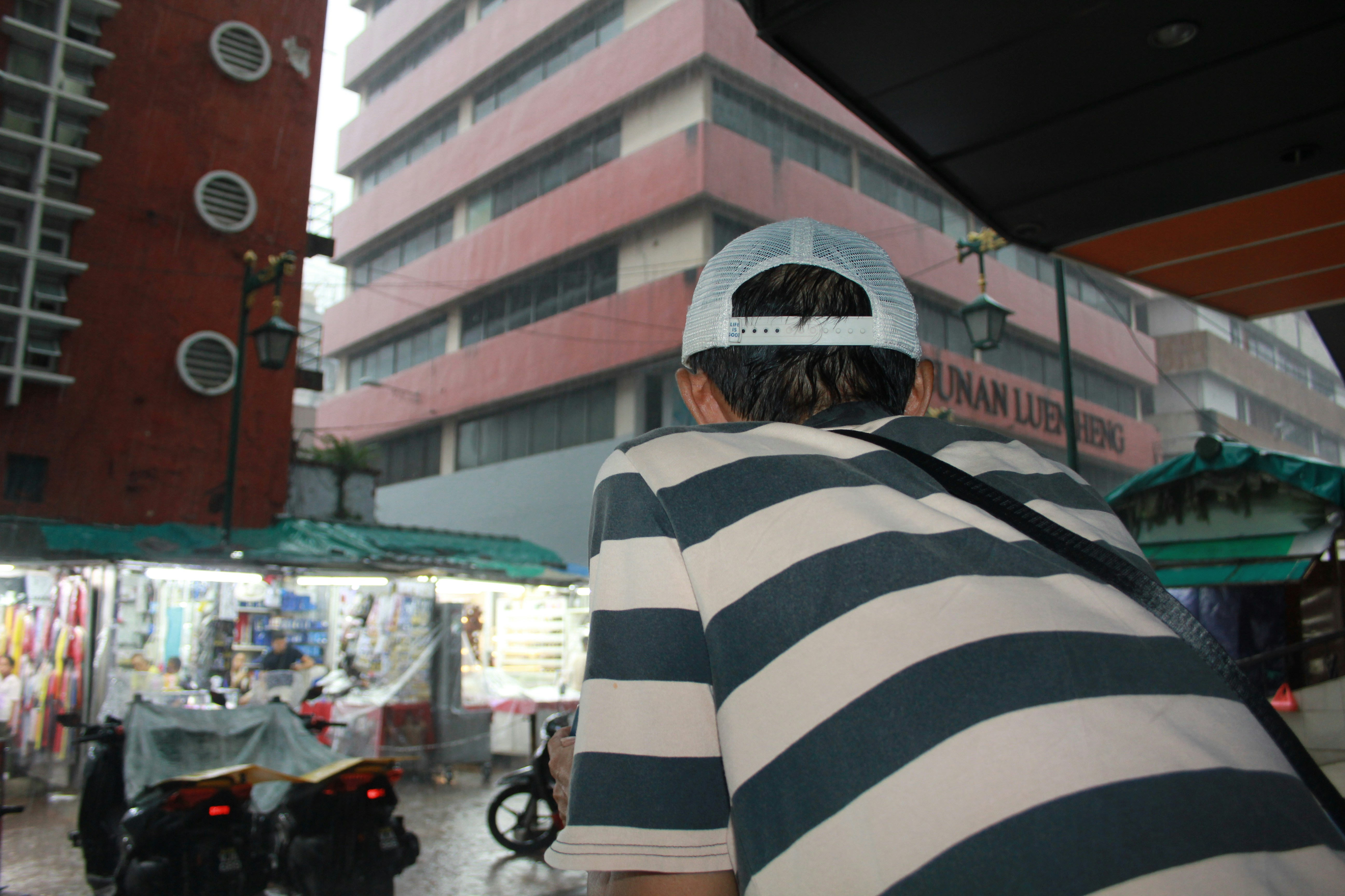 A man in a striped shirt is standing in front of a building