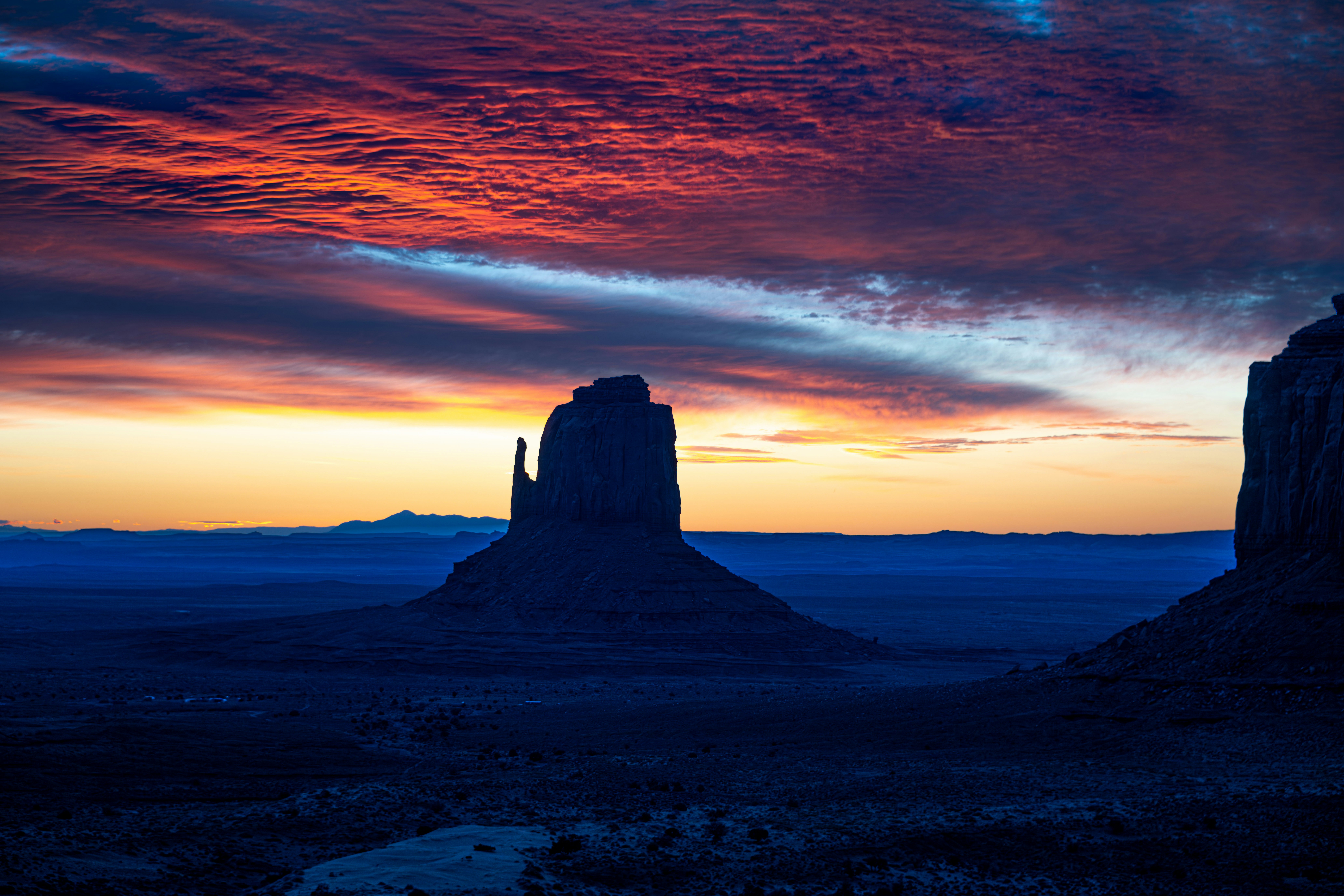 the sun is setting over the desert with mountains in the background