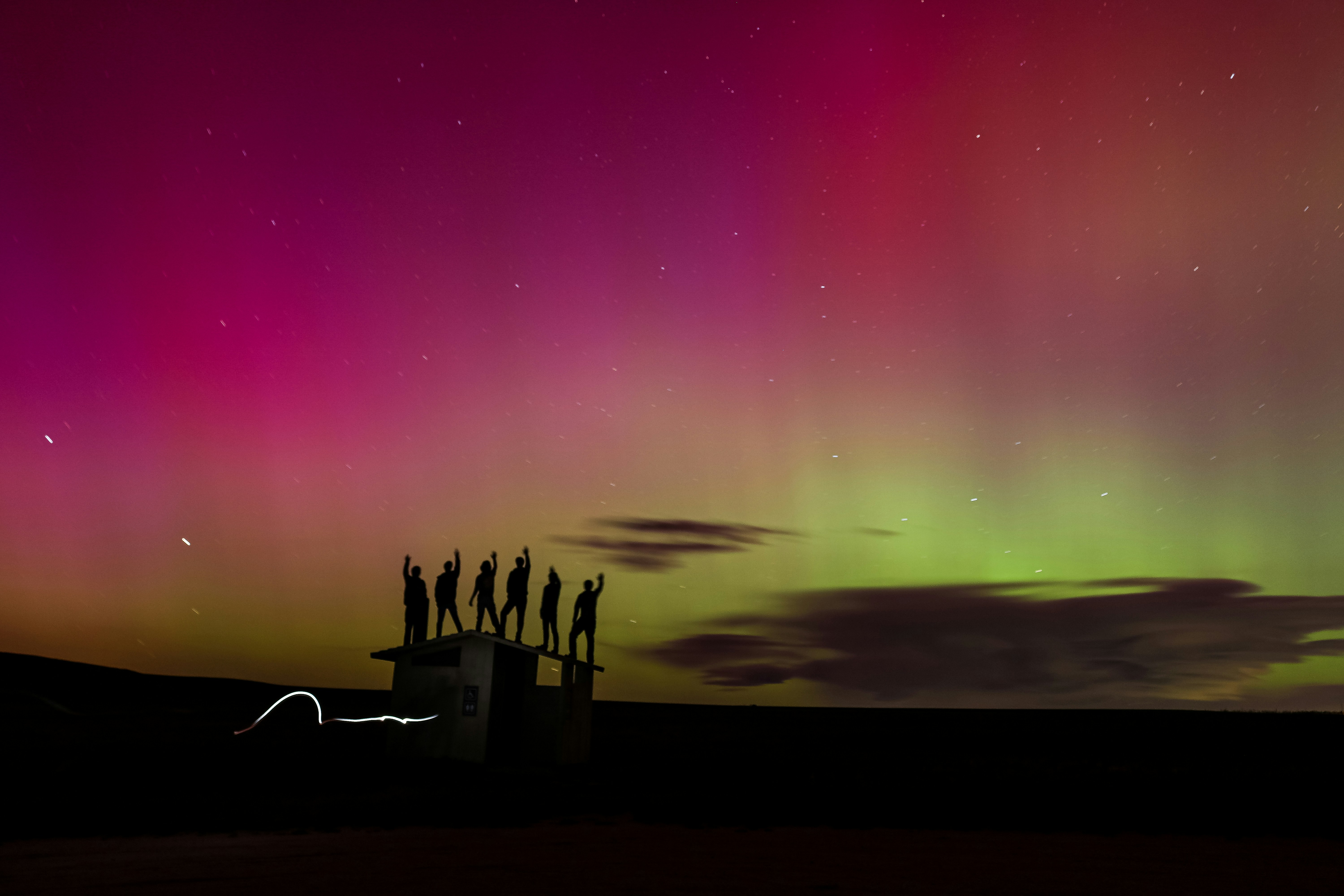 Un groupe de personnes debout au sommet d’un champ sous un ciel violet et vert