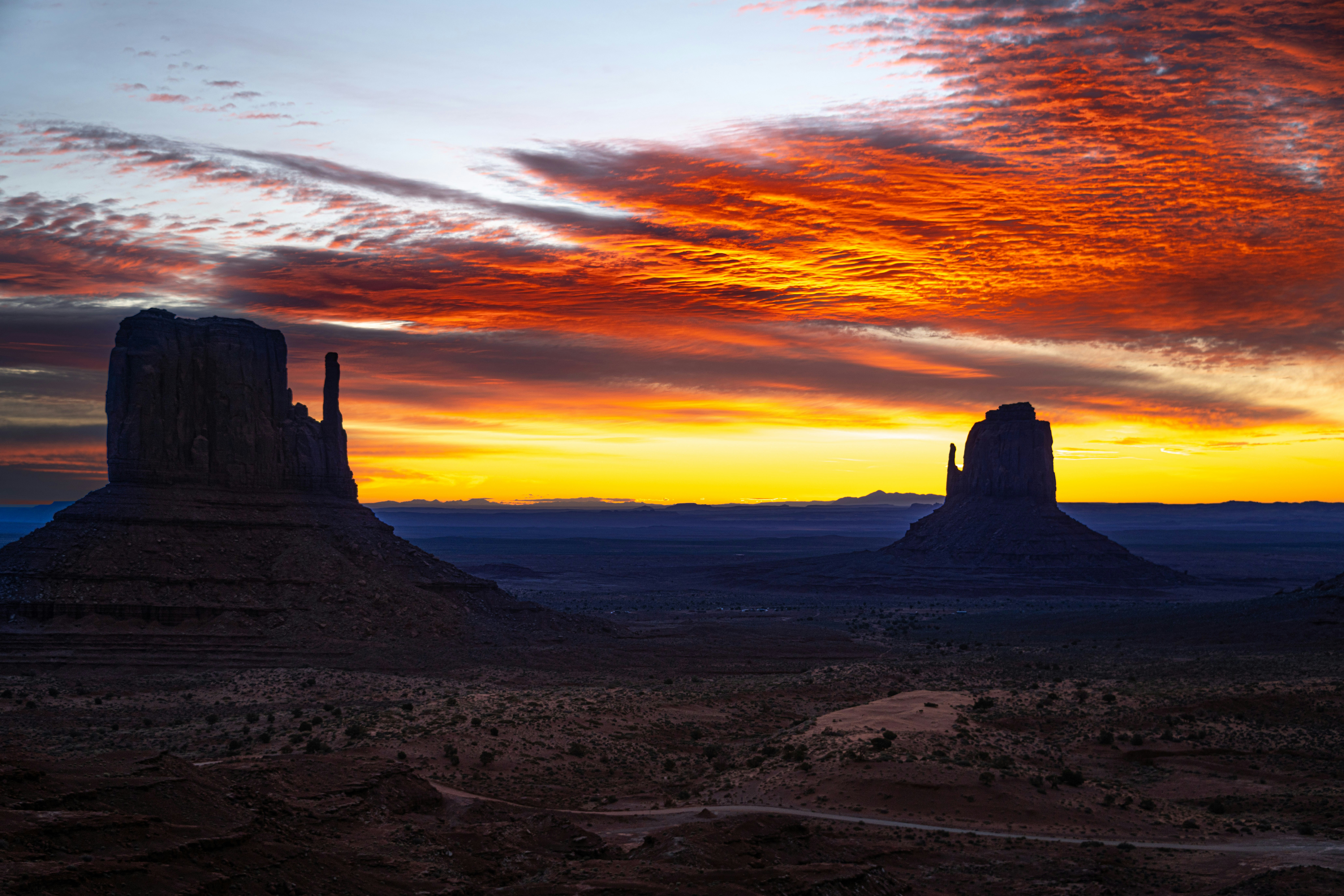 a sunset view of a desert with two large rocks in the foreground