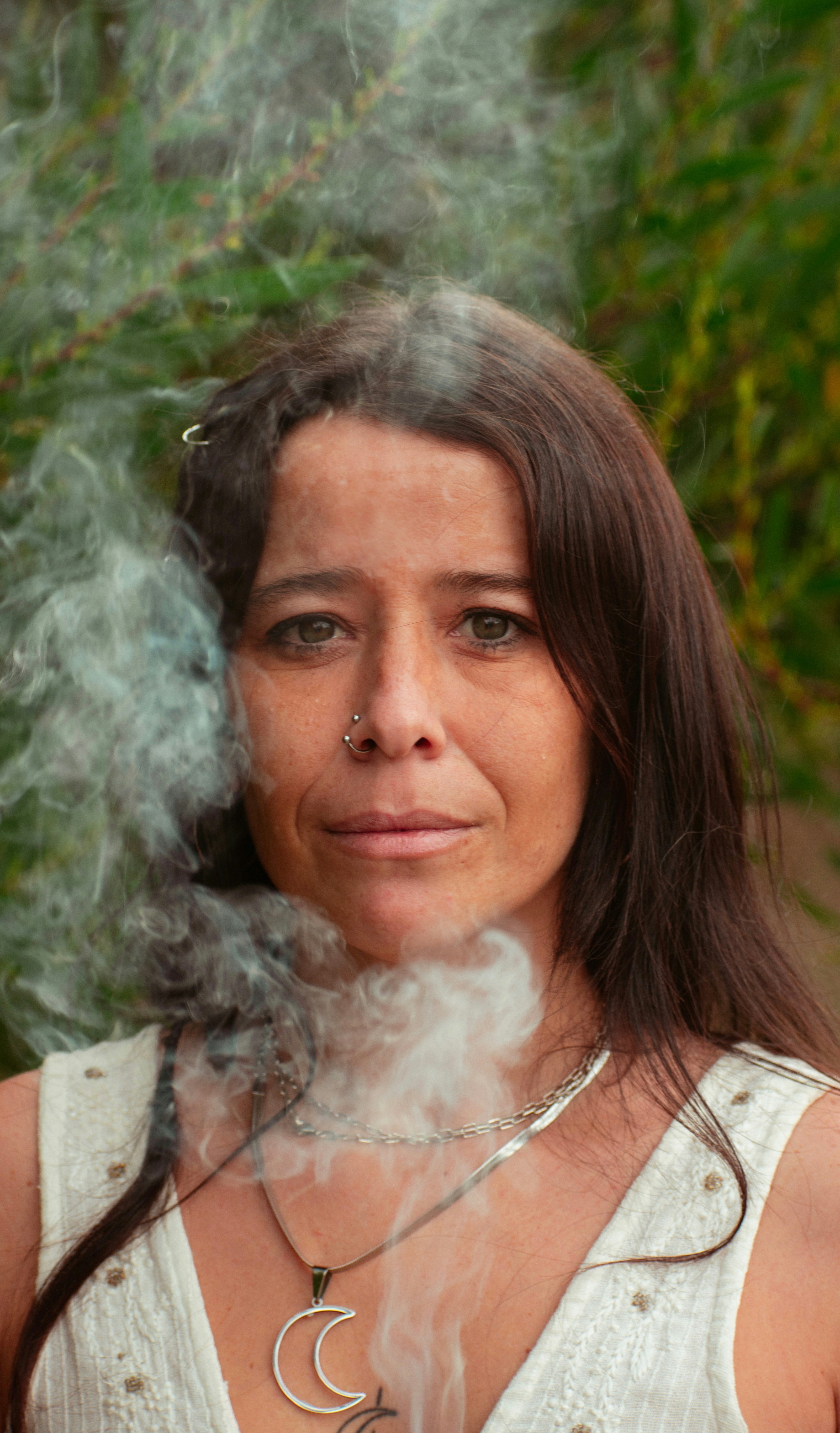 茂みの前でタバコを吸う女性