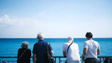 A group of people standing on top of a balcony next to the ocean