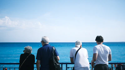 A group of people standing on top of a balcony next to the ocean