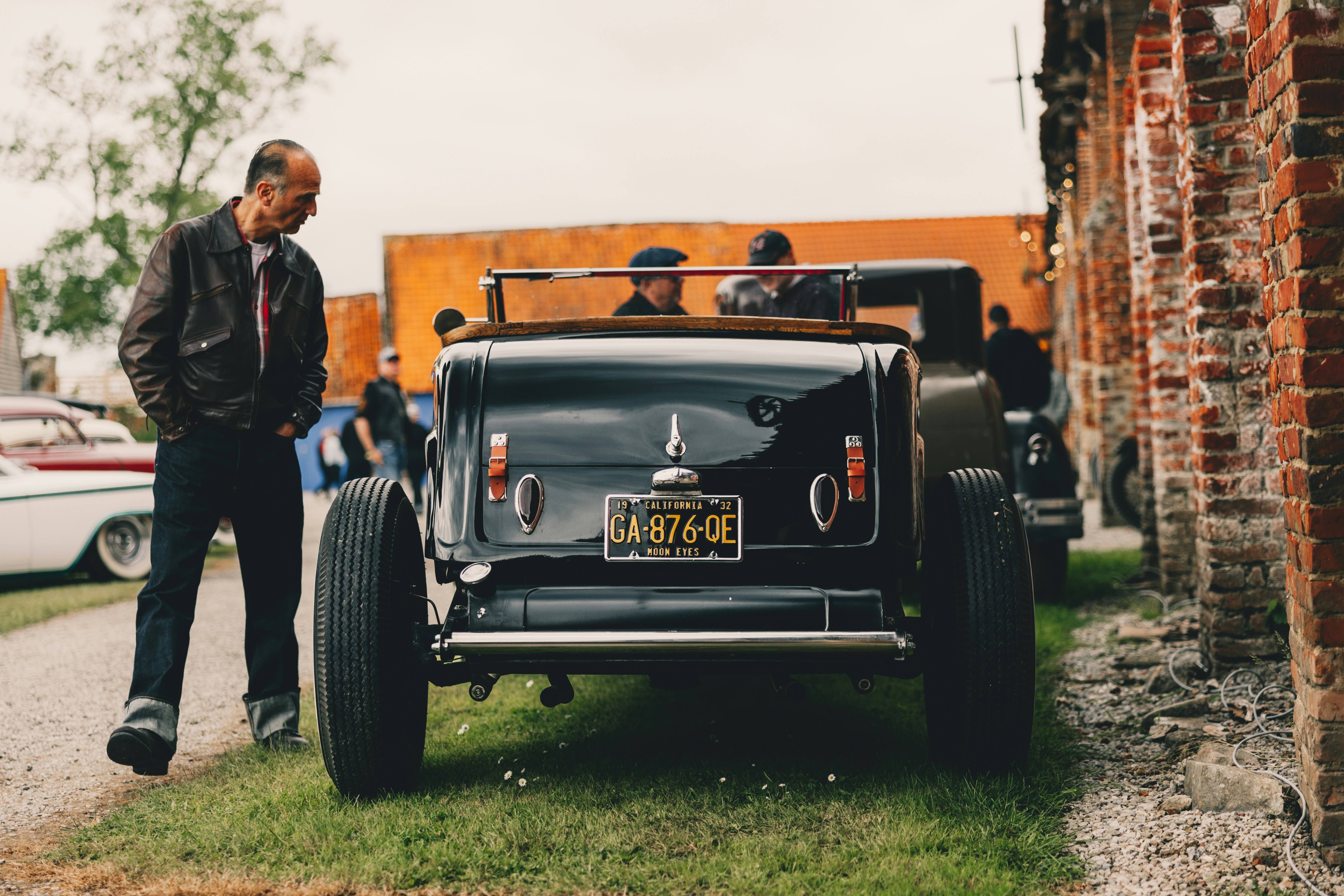A man standing next to an old fashioned car