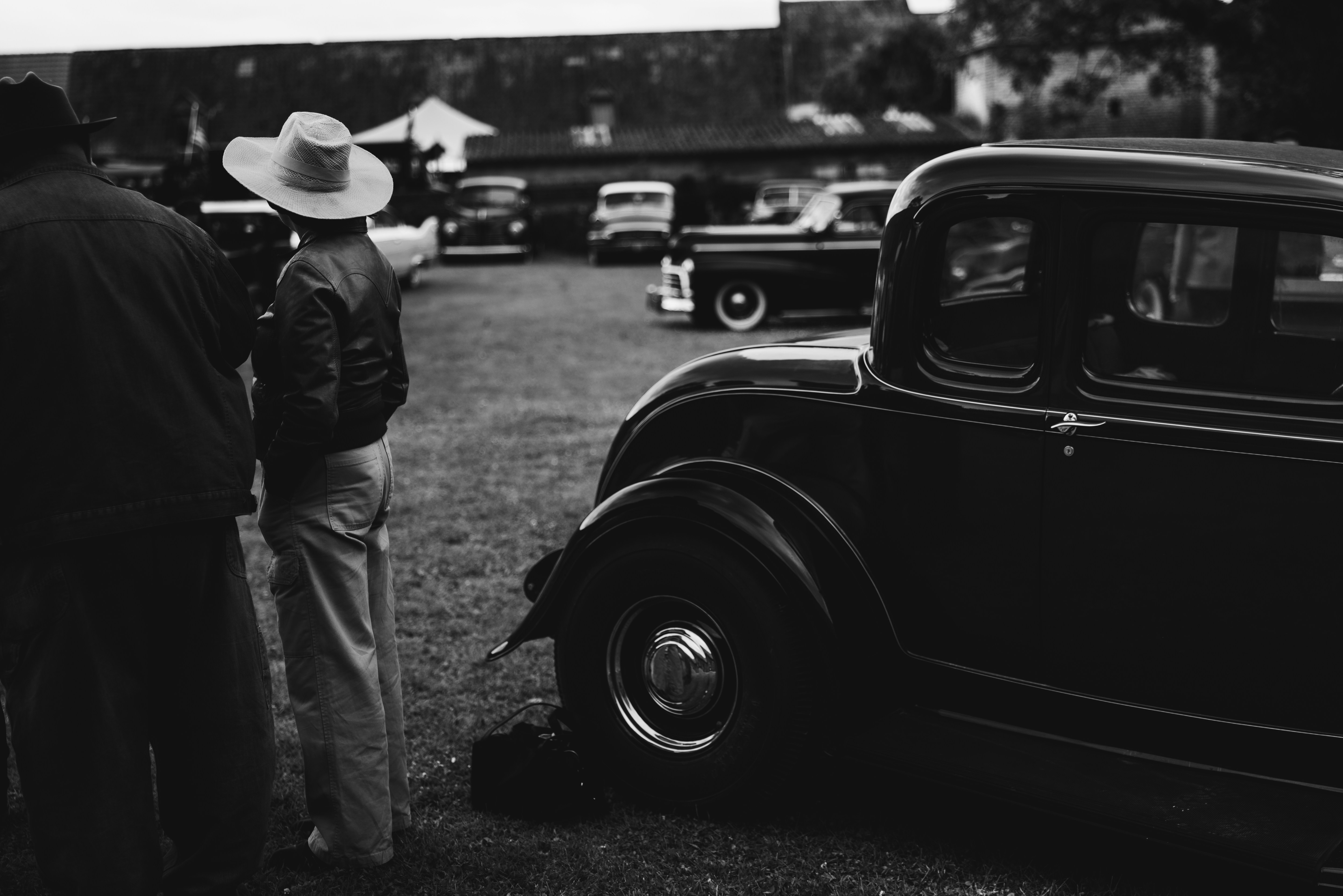 A black and white photo of people standing around a car