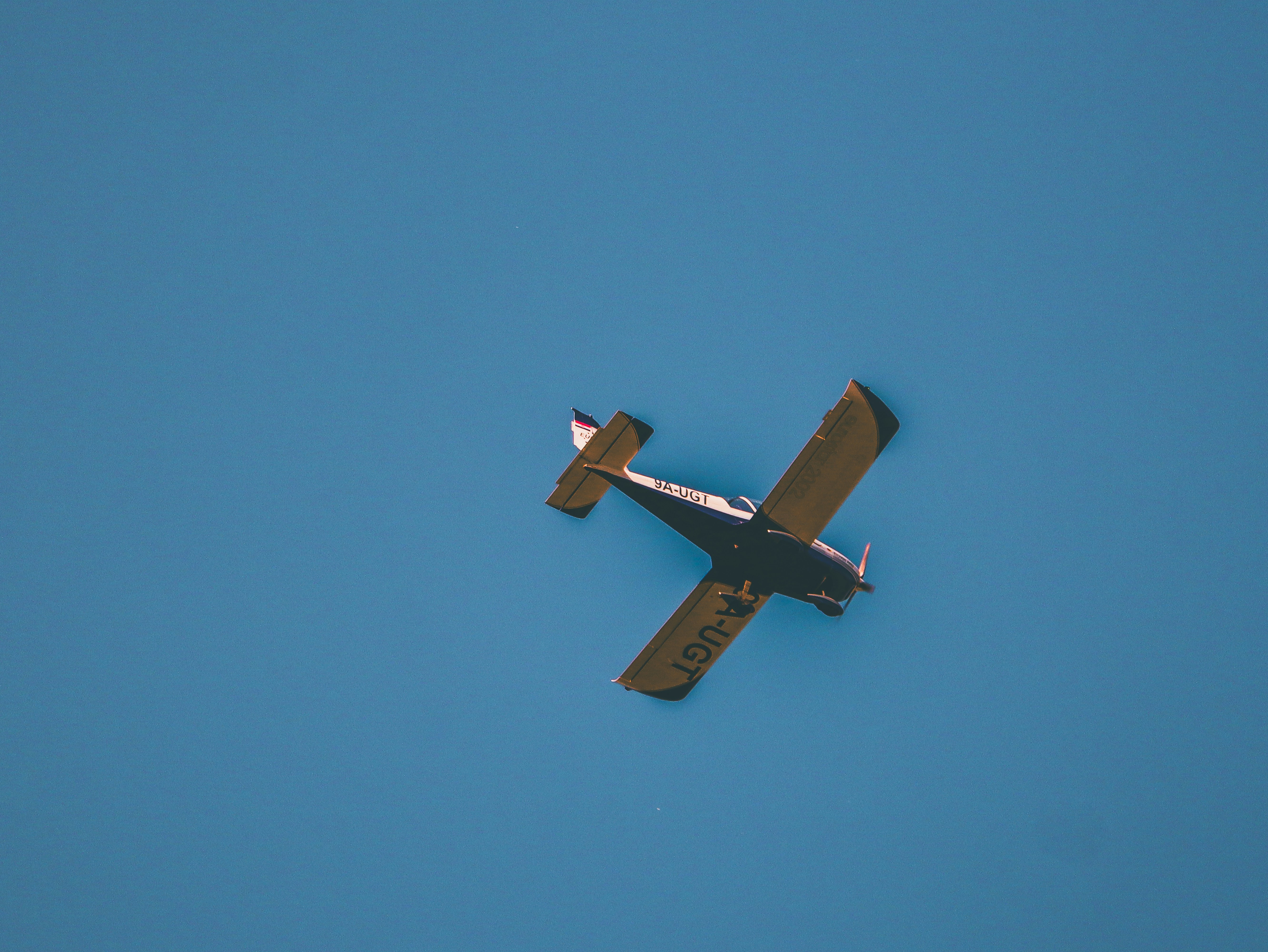 A small airplane flying through a blue sky