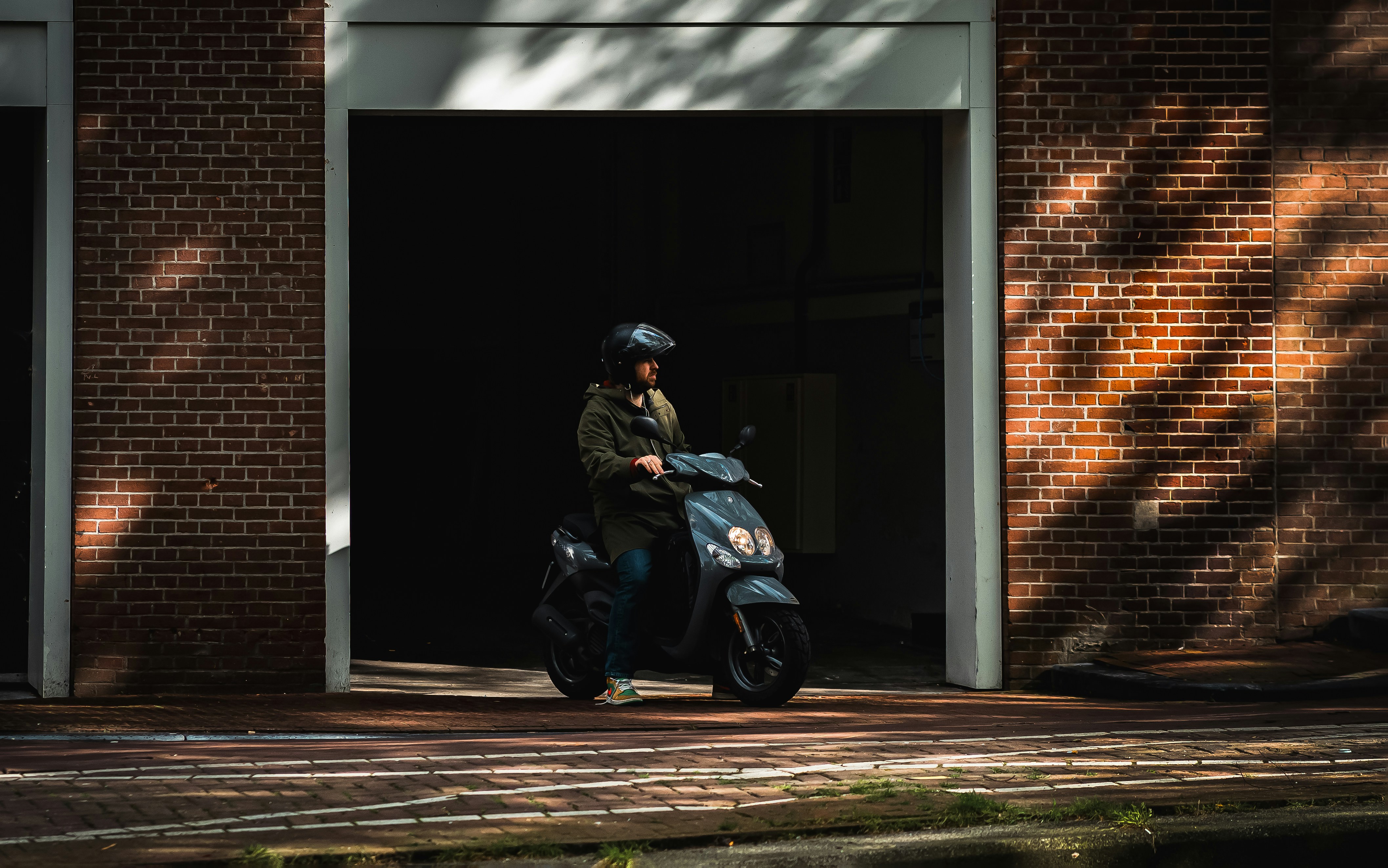 A person riding a motorcycle in front of a brick building