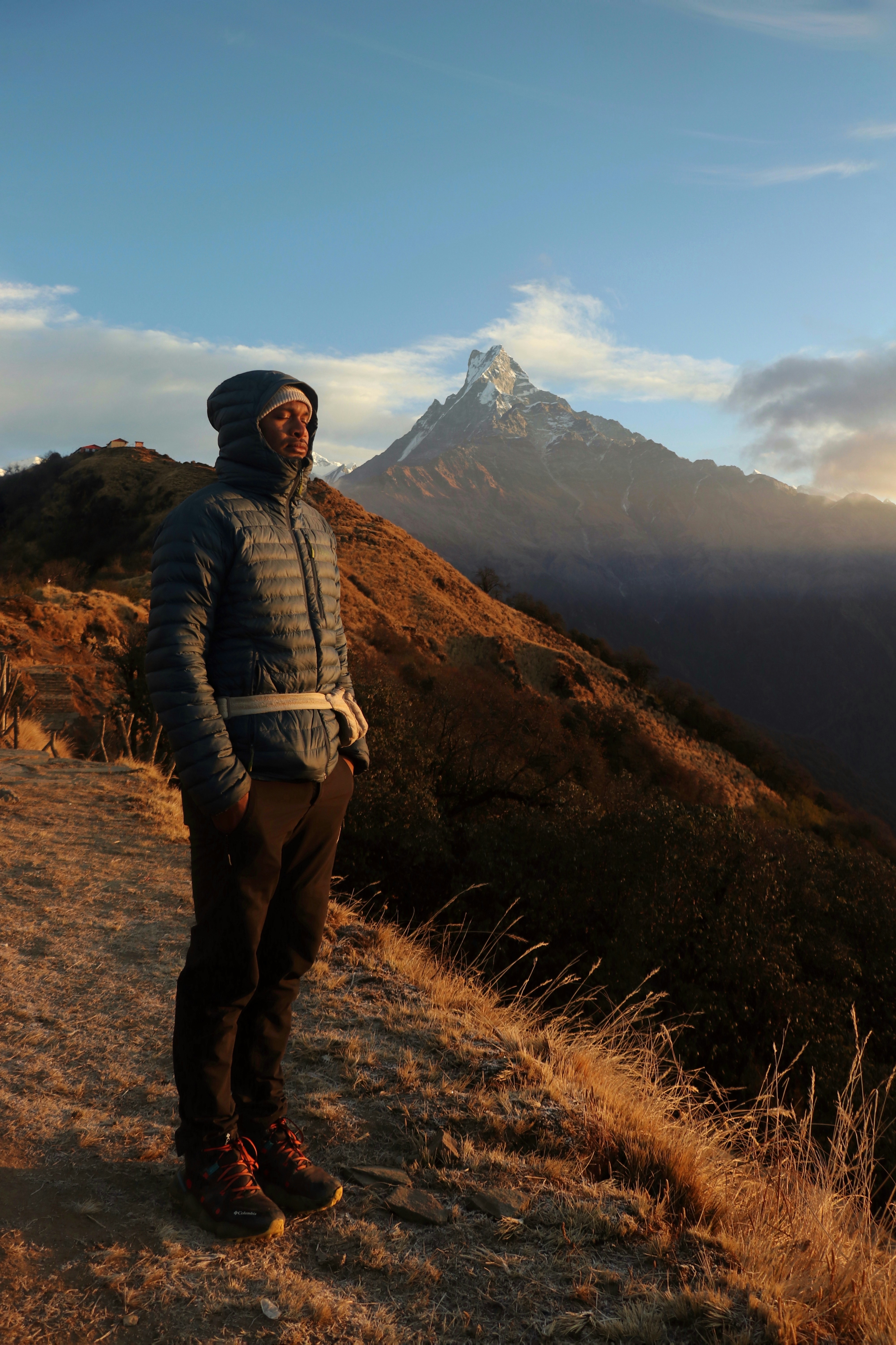 A man standing on a hill with a mountain in the background