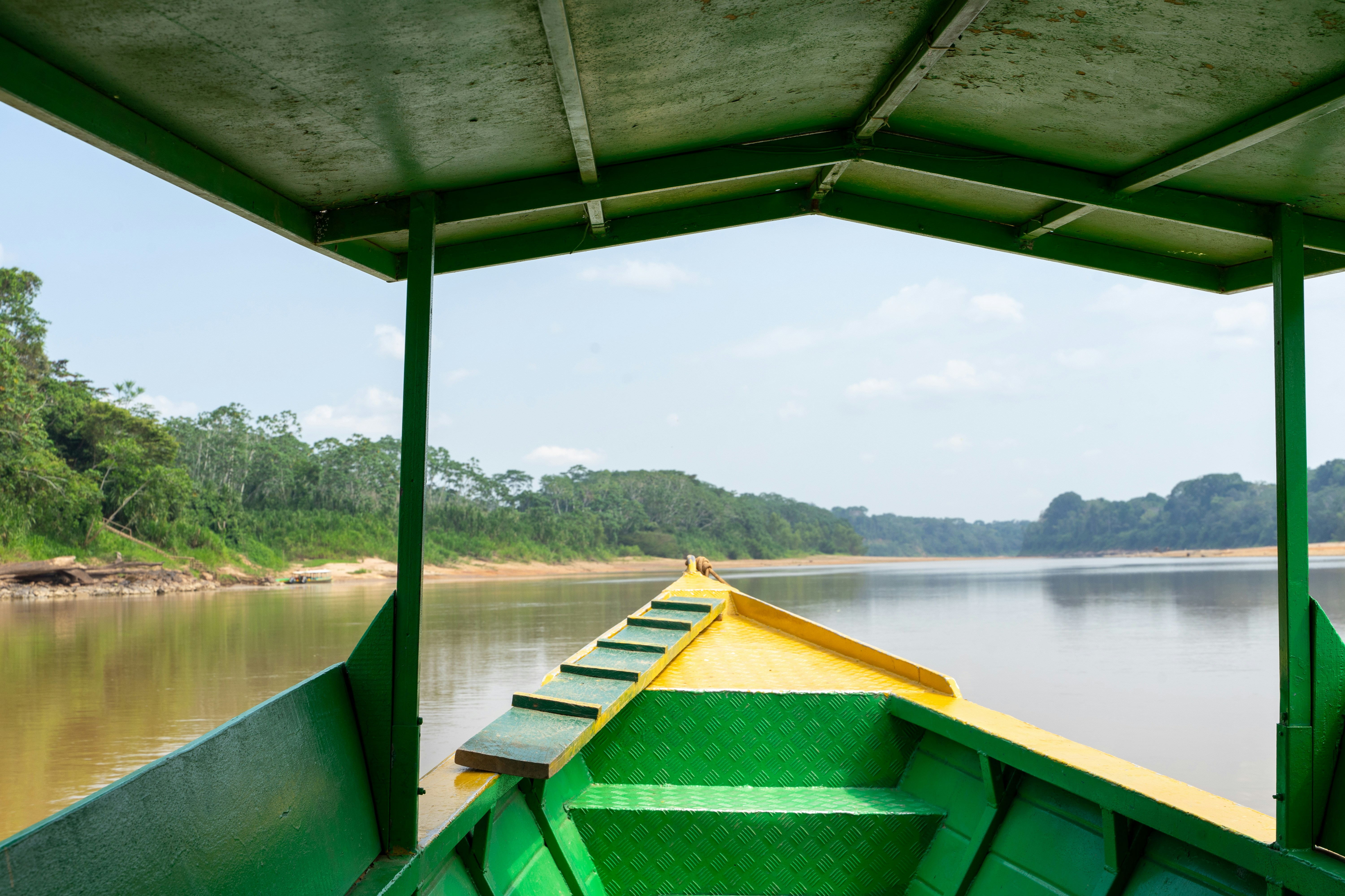 A green and yellow boat traveling down a river