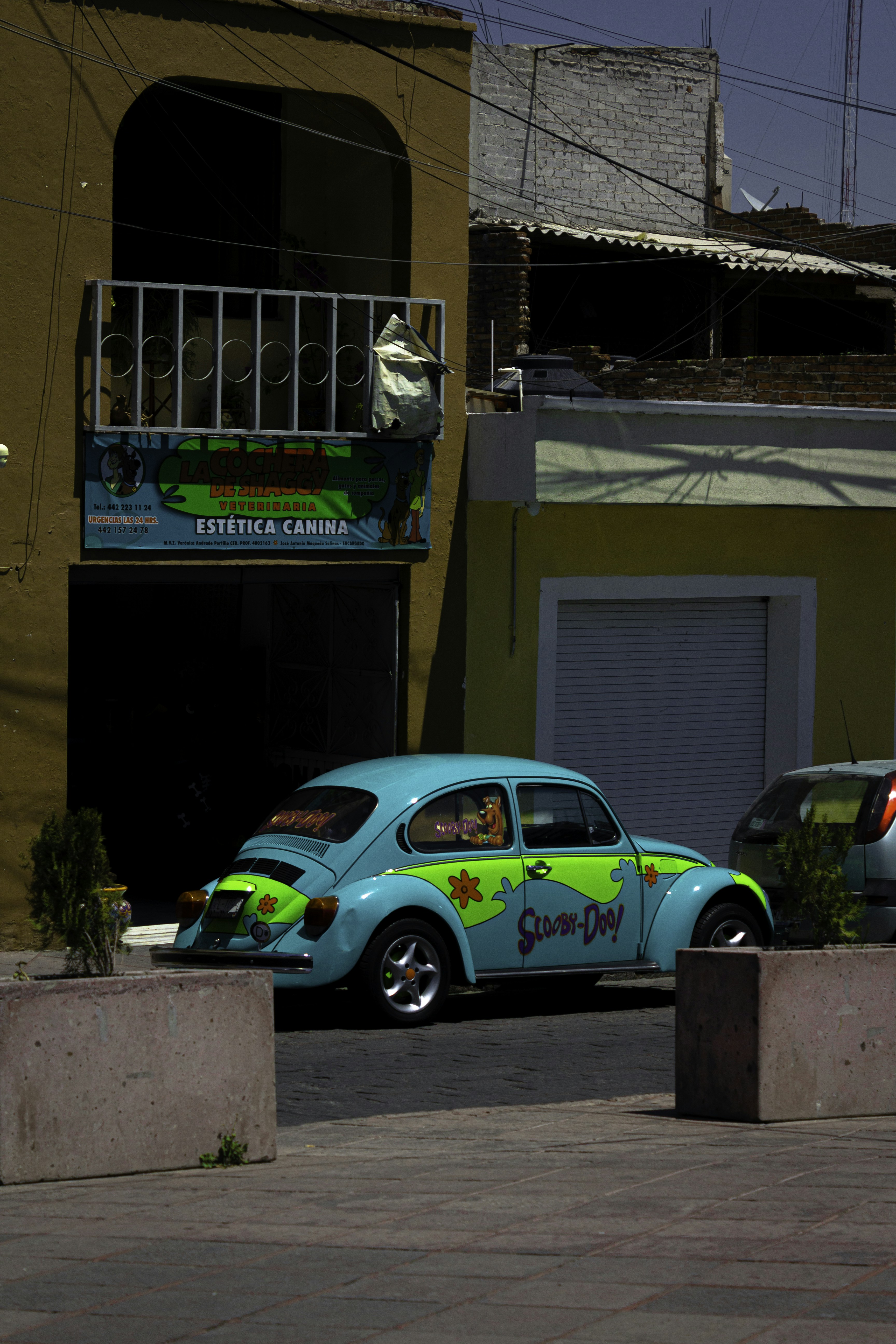 A blue and green car parked in front of a building