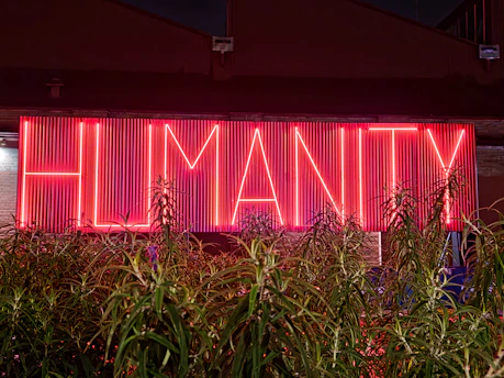a neon sign that reads, humanity in front of a building
