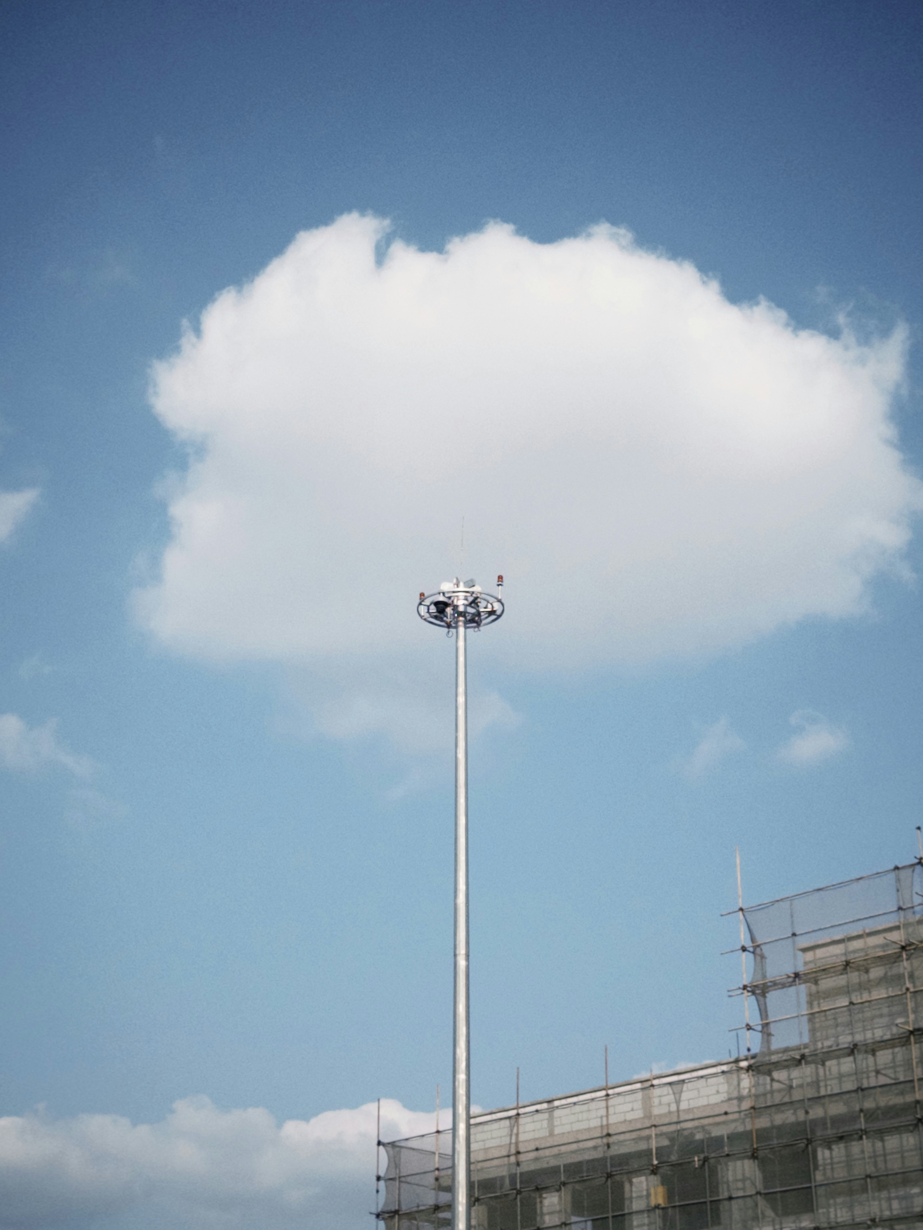 a tall light pole sitting under a cloudy blue sky