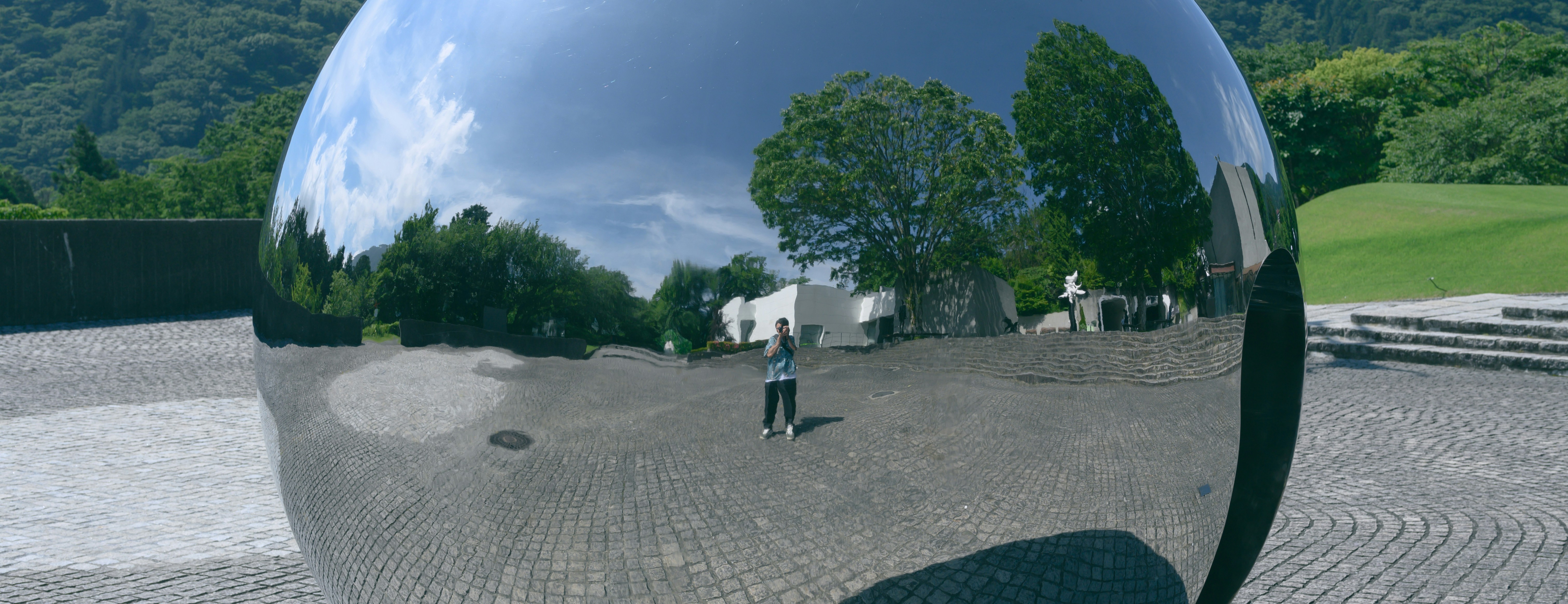 a person standing in front of a large metal ball