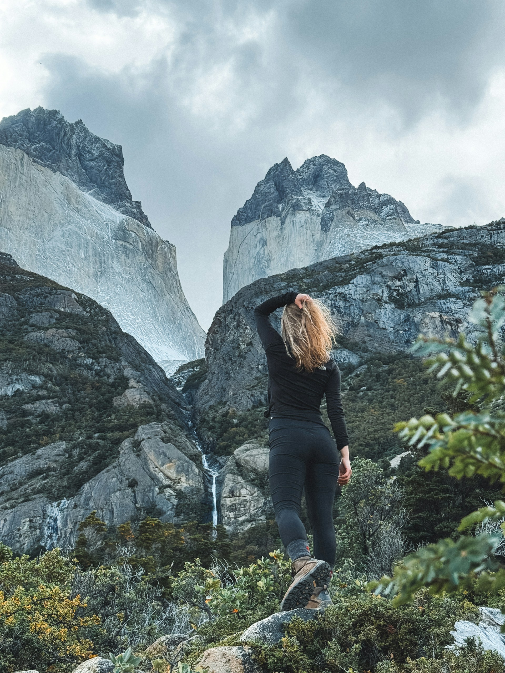 A woman standing on top of a lush green hillside