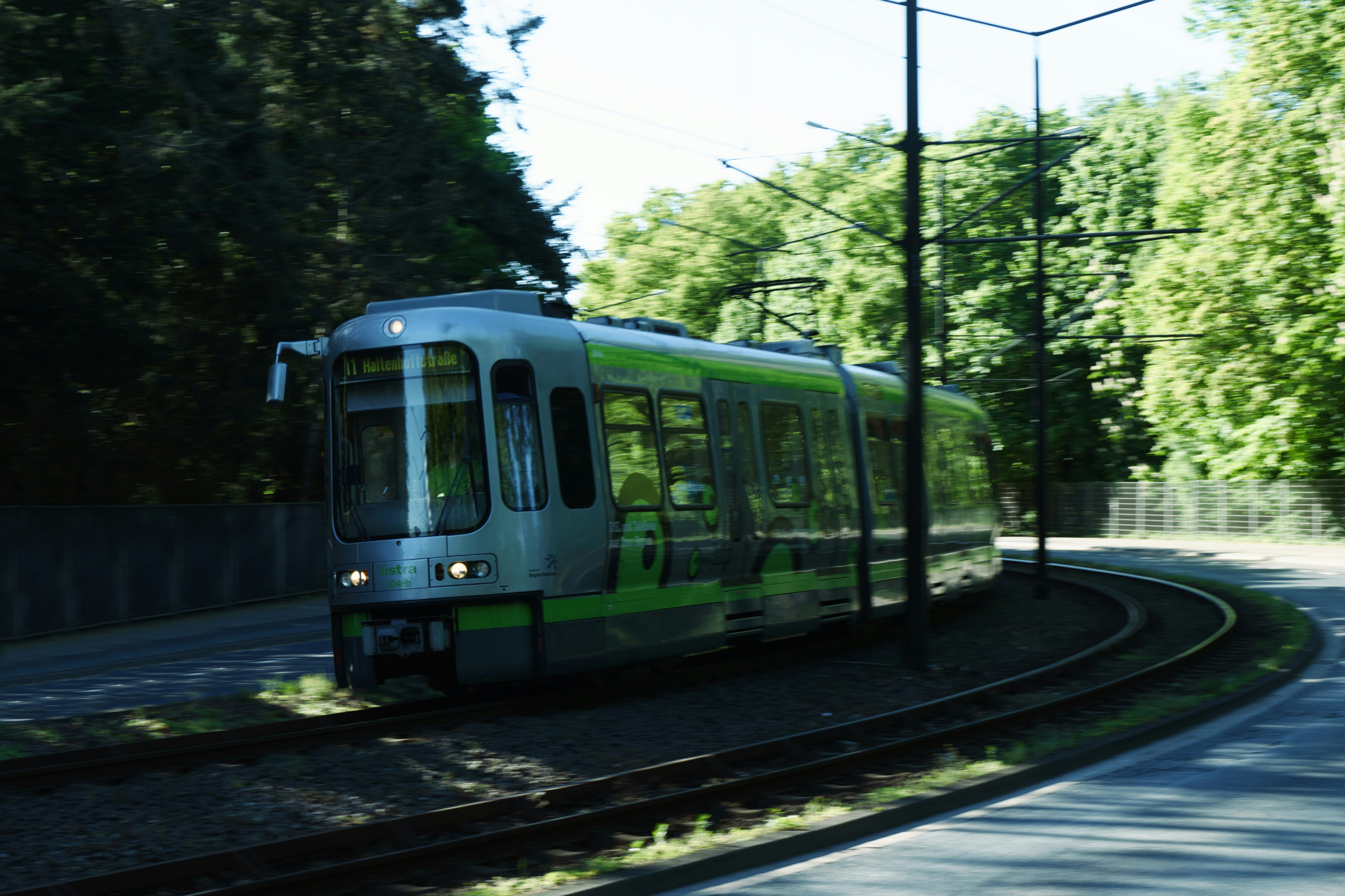 a green and white train traveling down train tracks