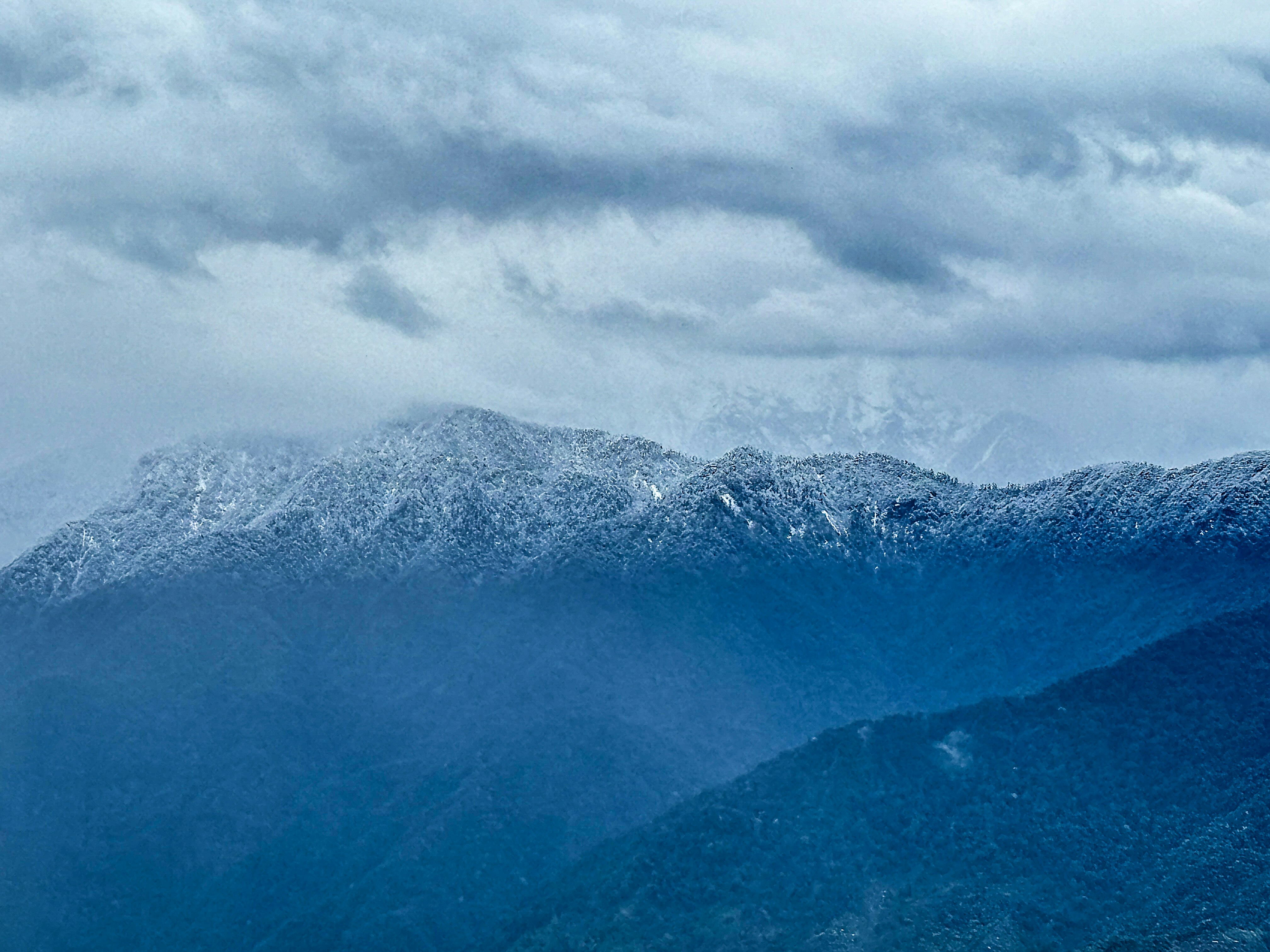 A snow covered mountain range under a cloudy sky