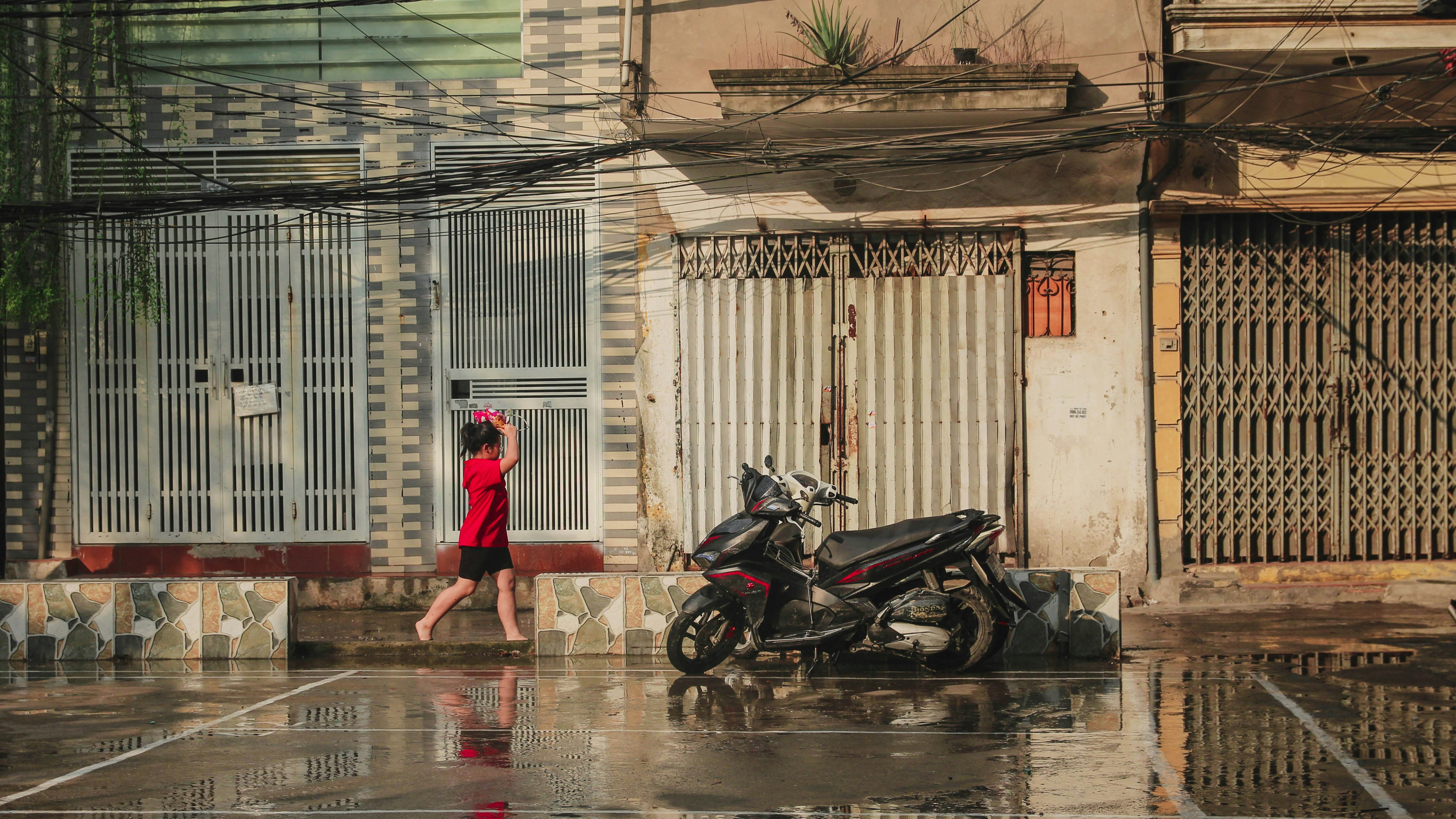 a woman in a red dress walking past a motorcycle