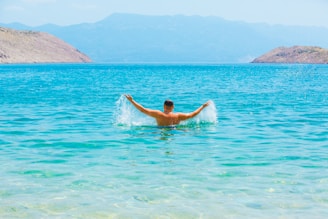 A man swimming in a lake with mountains in the background